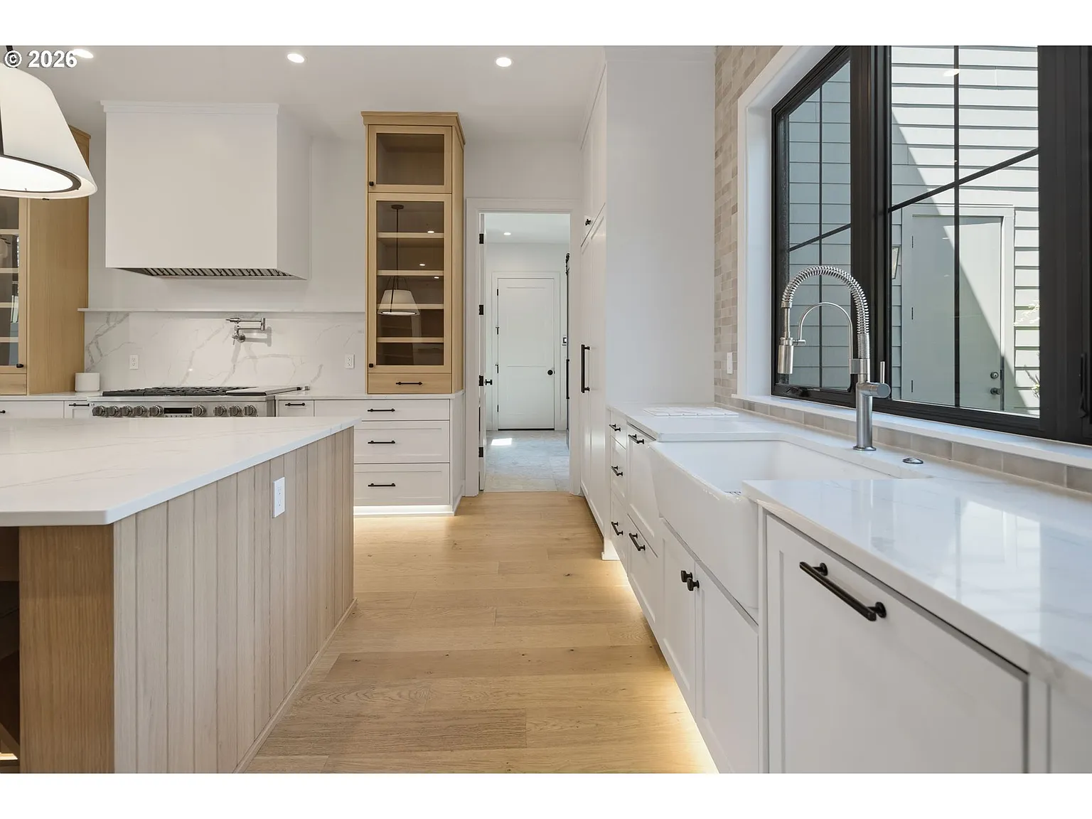 The far side of the kitchen centers the sink beneath a black-framed window.