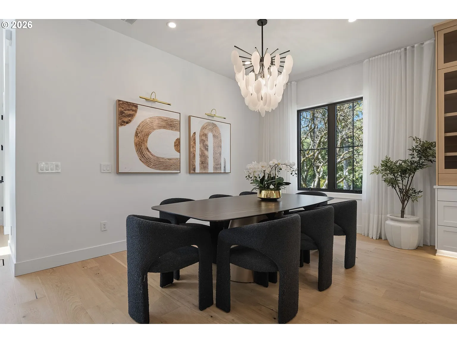 The dining area features a rectangular dark wood table surrounded by sculptural upholstered chairs.