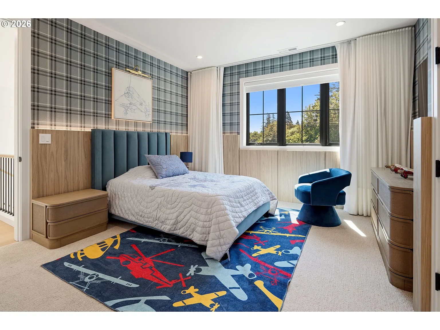 Bedroom with blue-gray plaid wallpaper with warm wood paneling along the lower half of the room.
