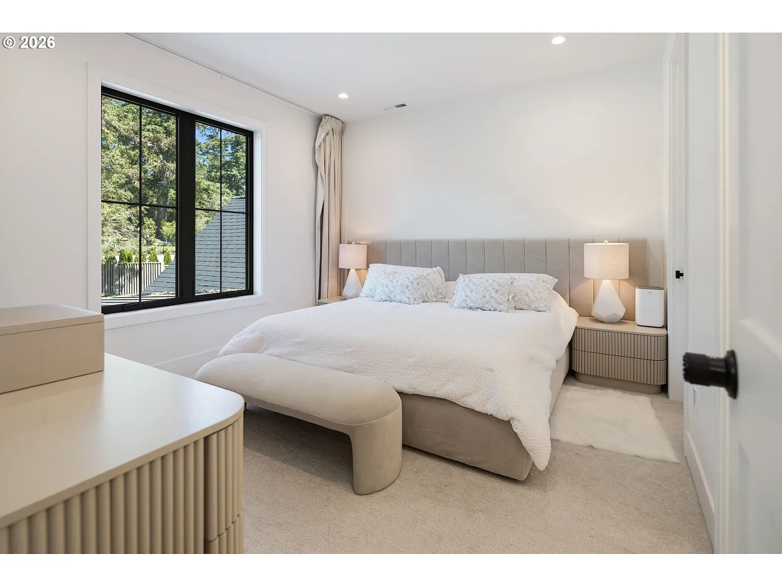 The third bedroom has a much warmer neutral palette with a large upholstered bed centered between rounded nightstands.
