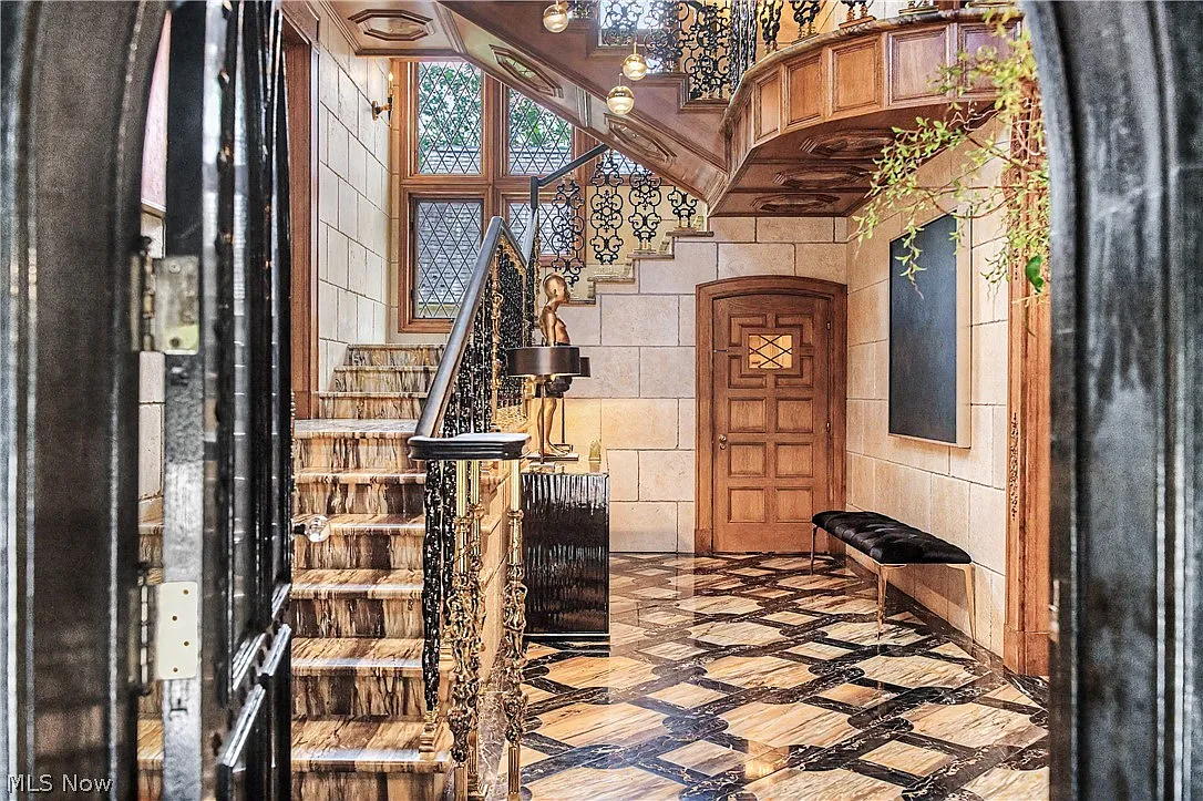 Imported marble runs across the floor in a dramatic geometric pattern and continues up the stair treads.