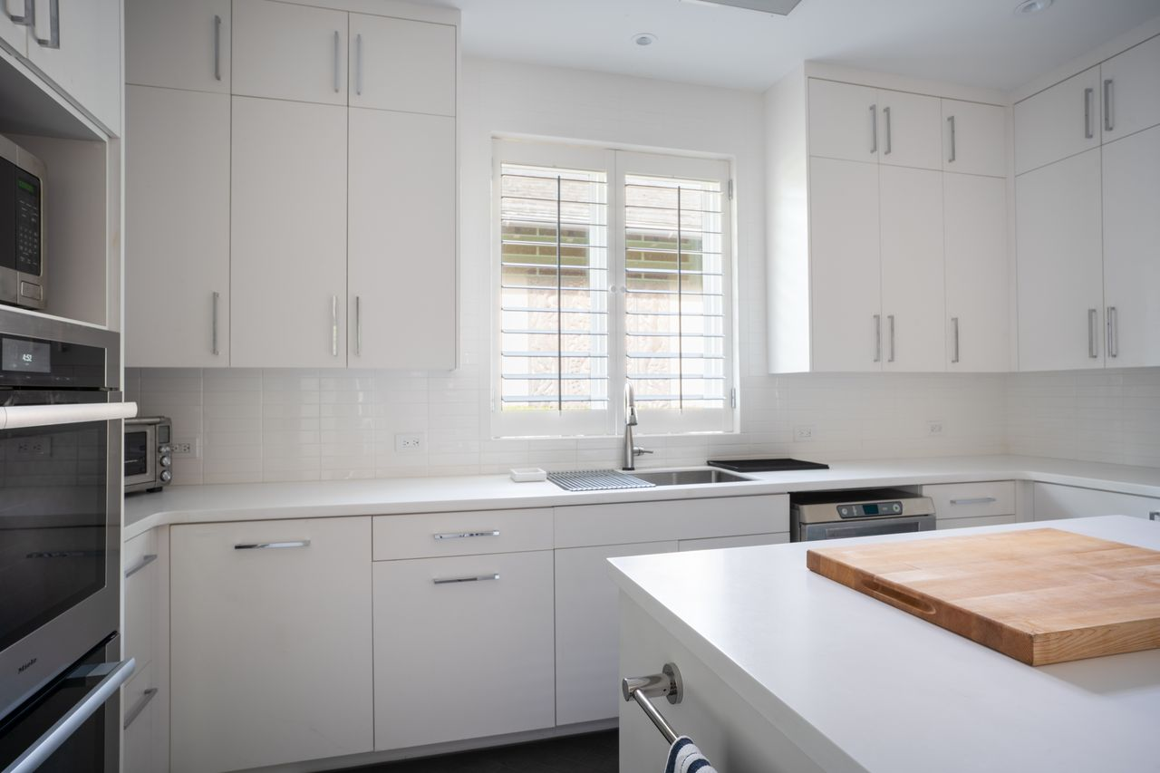 Built-in ovens, a wide cooktop, and an oversized vent hood give the kitchen a more commercial-minded setup.