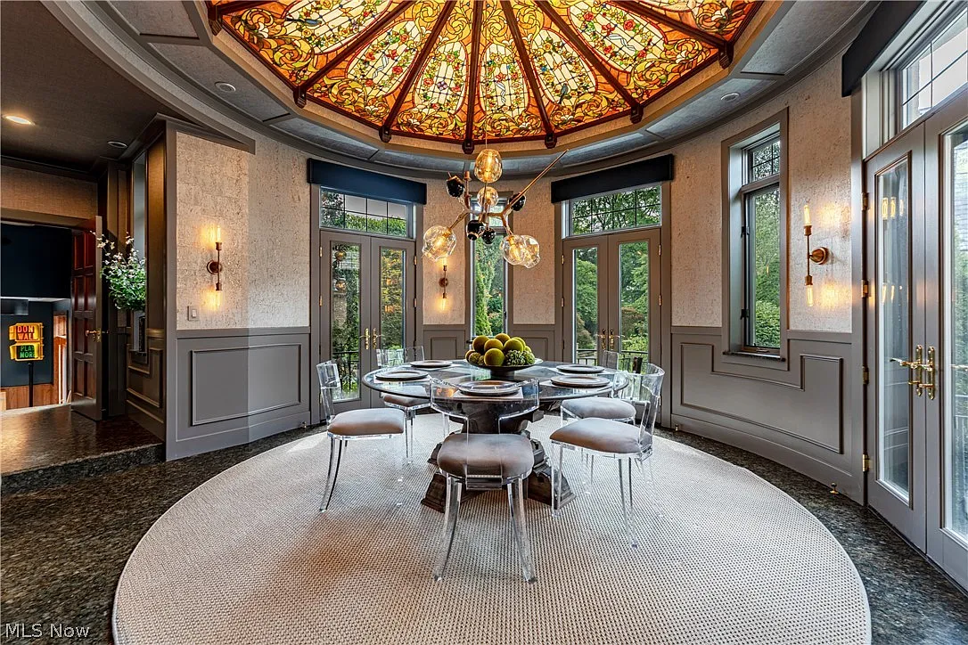 The next room opens into a formal dining space set beneath a custom Tiffany stained-glass skylight. 