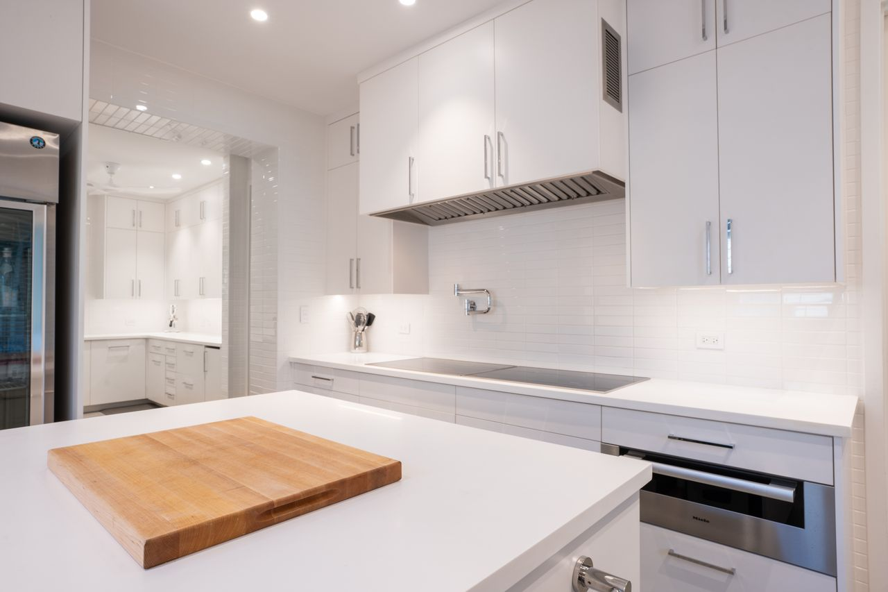 Chef's kitchen arranged around a central island, with white cabinetry running nearly floor to ceiling and long stretches of counter space wrapping the perimeter.
