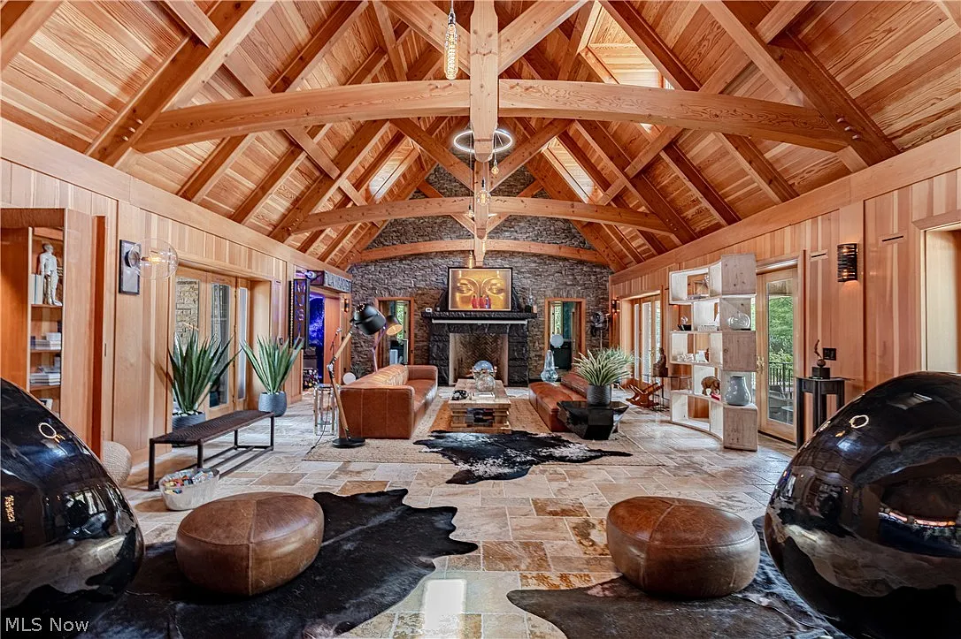 Circular chairs and leather ottomans are positioned closer to the bar before the room extends toward additional sofas and a large fireplace at the far end.