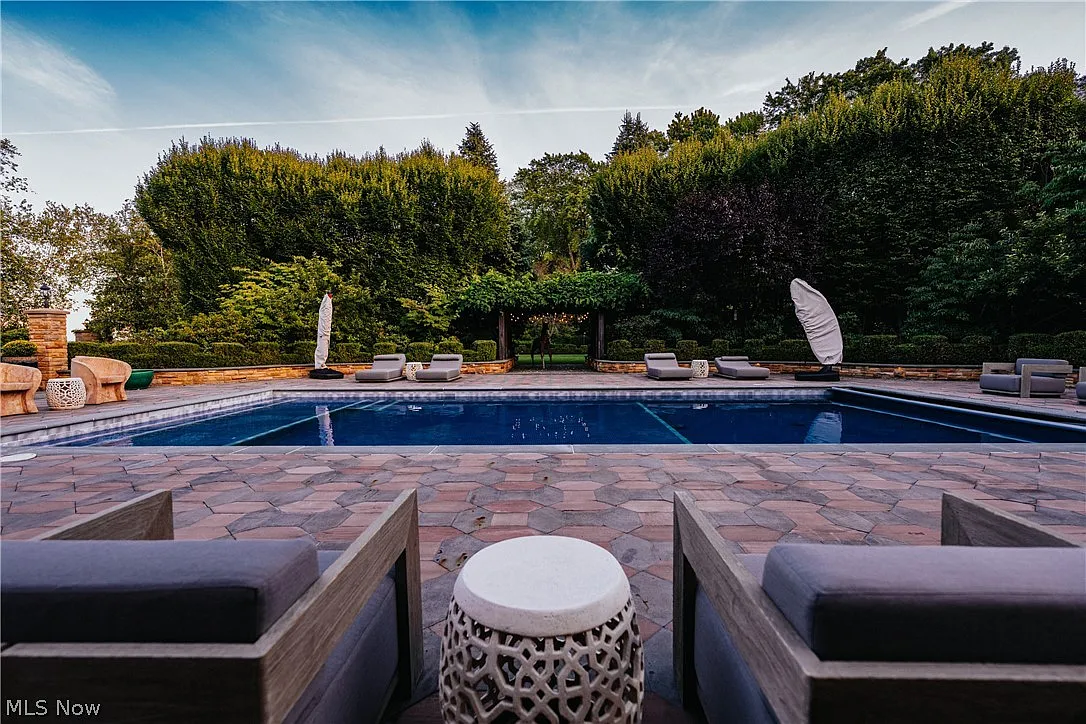 A rectangular swimming pool set close to the entertainment wing with lounge seating arranged around the water.