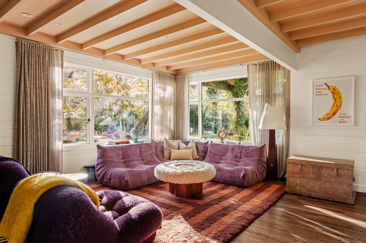 A corner living room wrapped by windows on two sides, offering views of the front and side yards. 