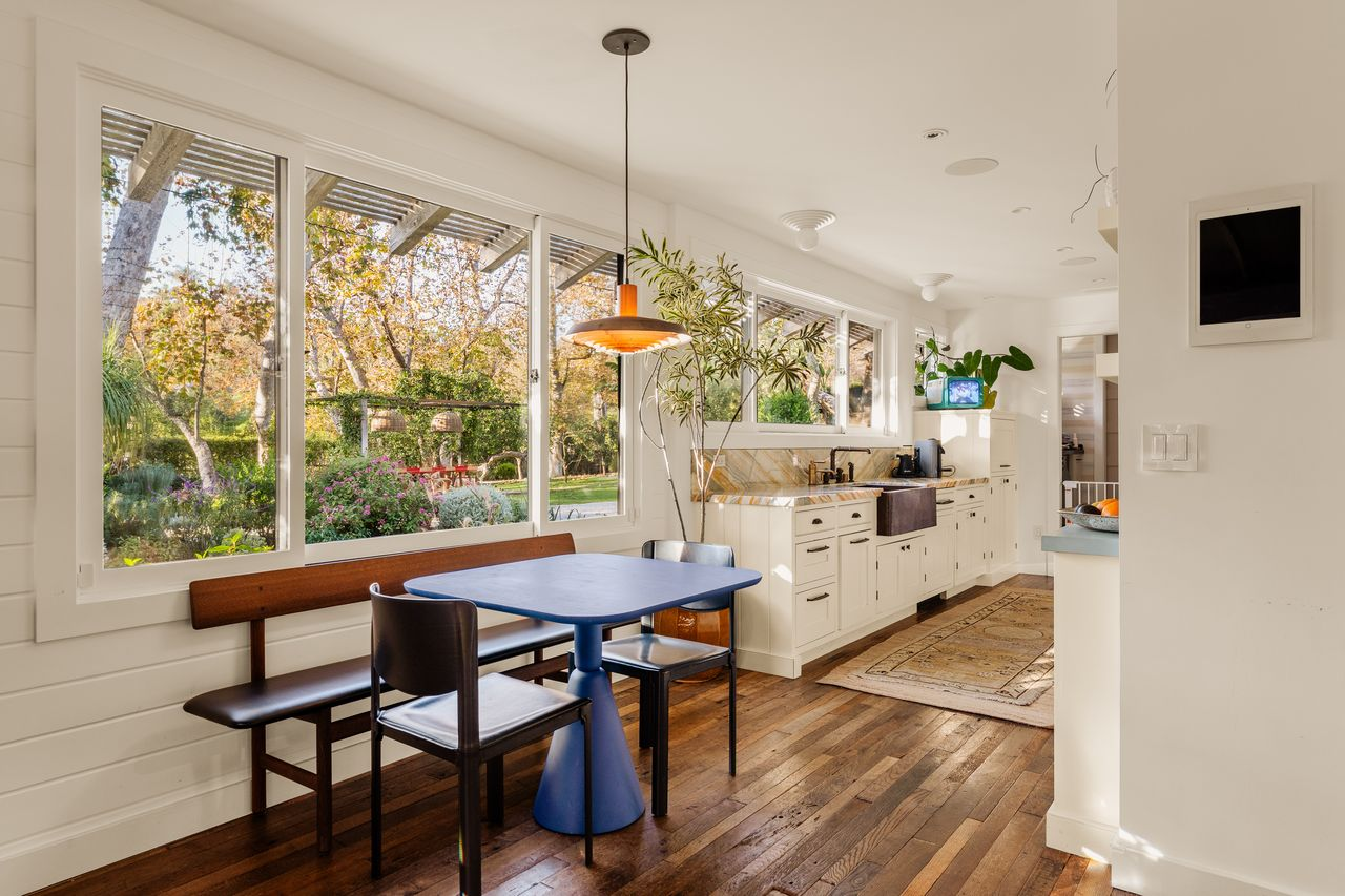 At the far end, the kitchen opens into a casual breakfast area positioned beside a long wall of windows.