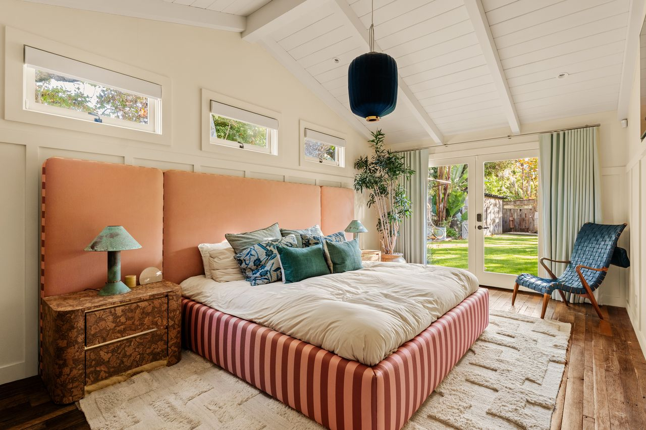 The bed is placed in the center of the room across from a set of glass doors that open to the backyard.