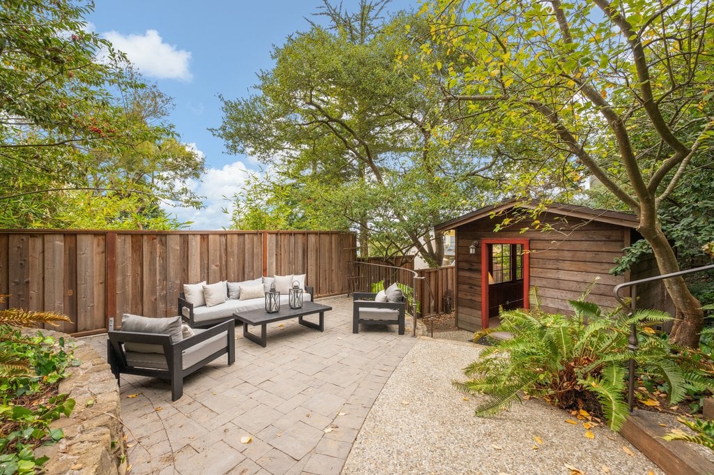 A paved patio sits beneath the trees at the center of the lot.