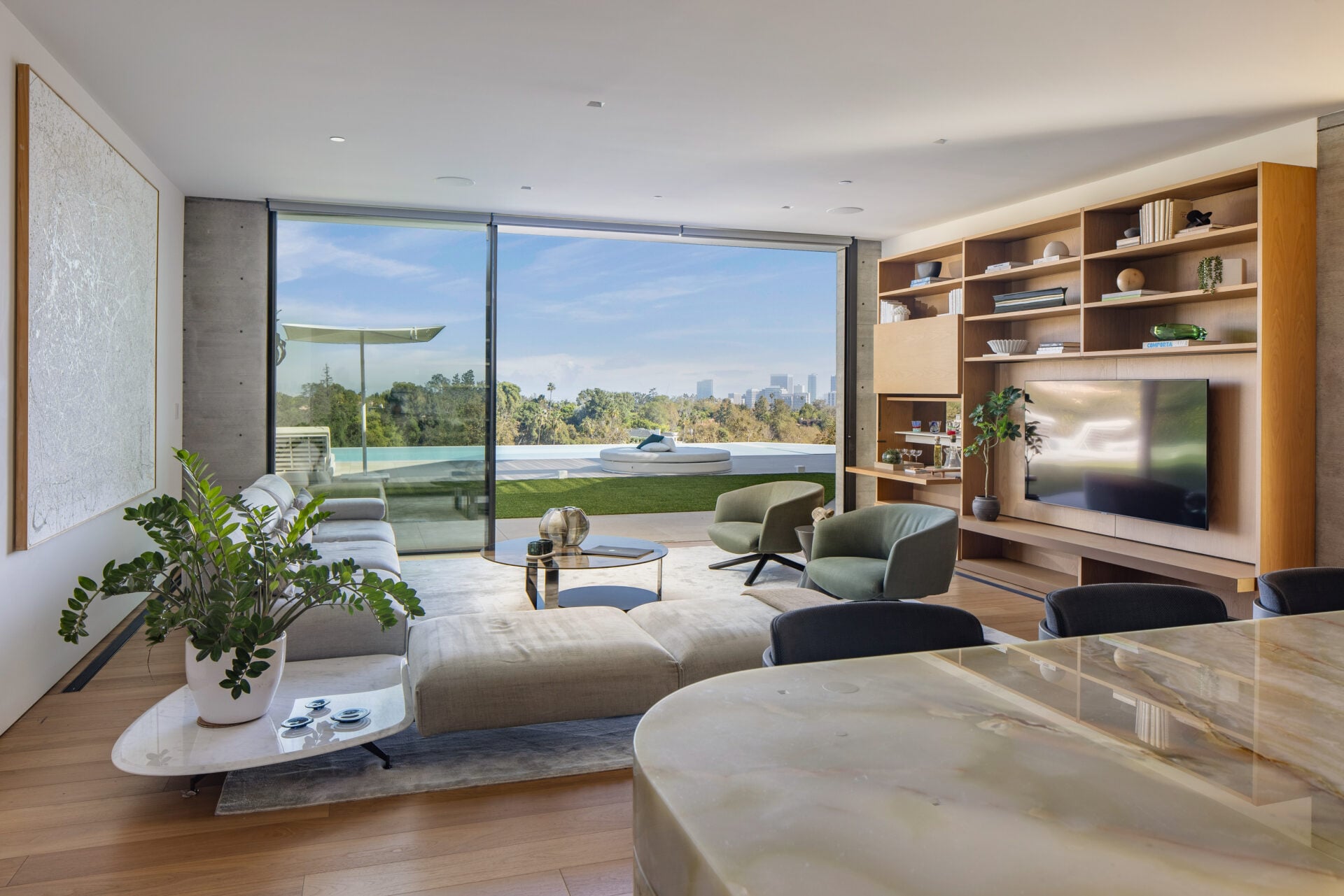 Floor-to-ceiling glass opens the lounge directly to the pool terrace, allowing the seating area to face both the television and the outdoor view.