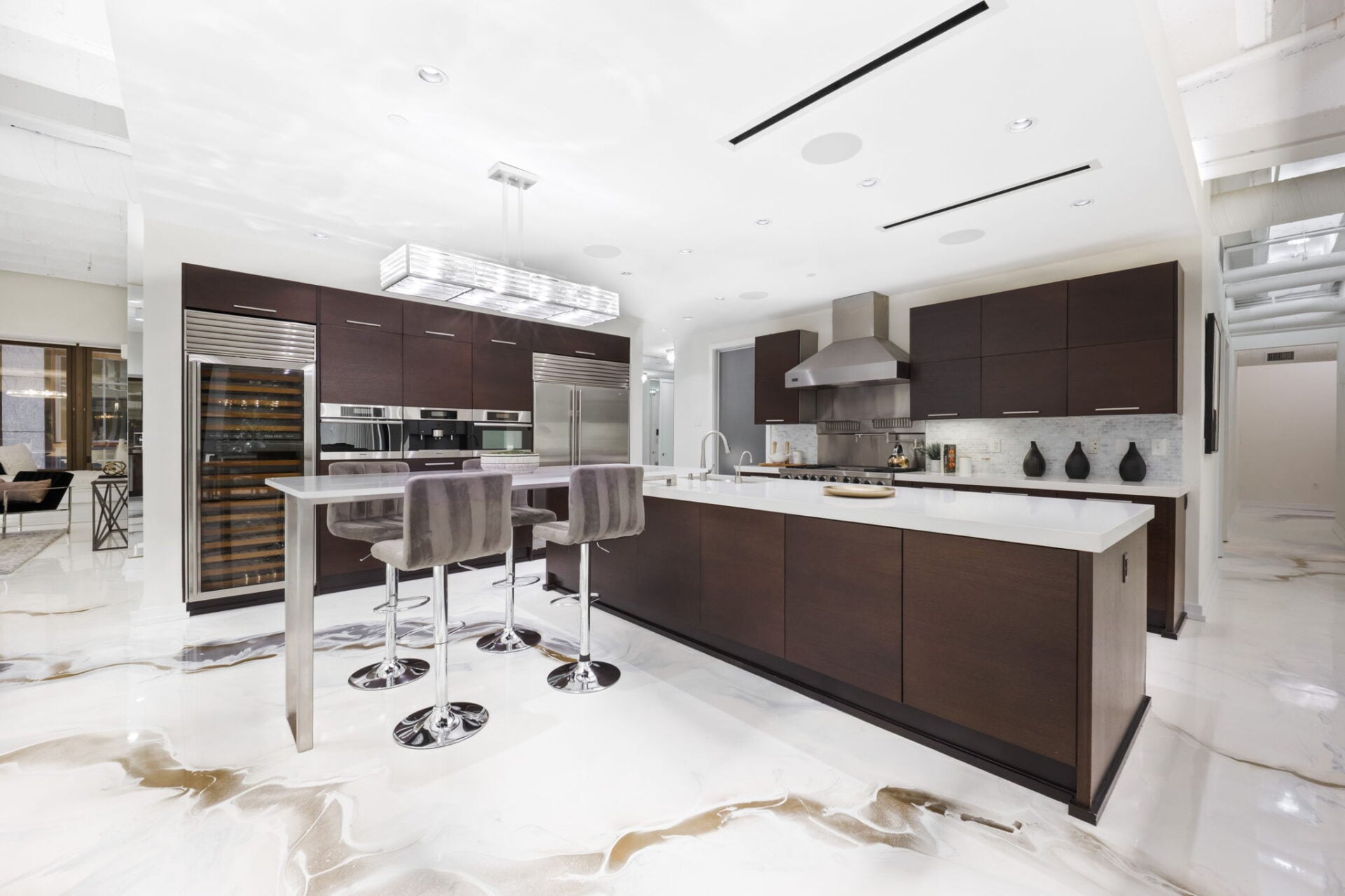 The great room opens with an oversized waterfall-style island that has an extended bar top table along one side.