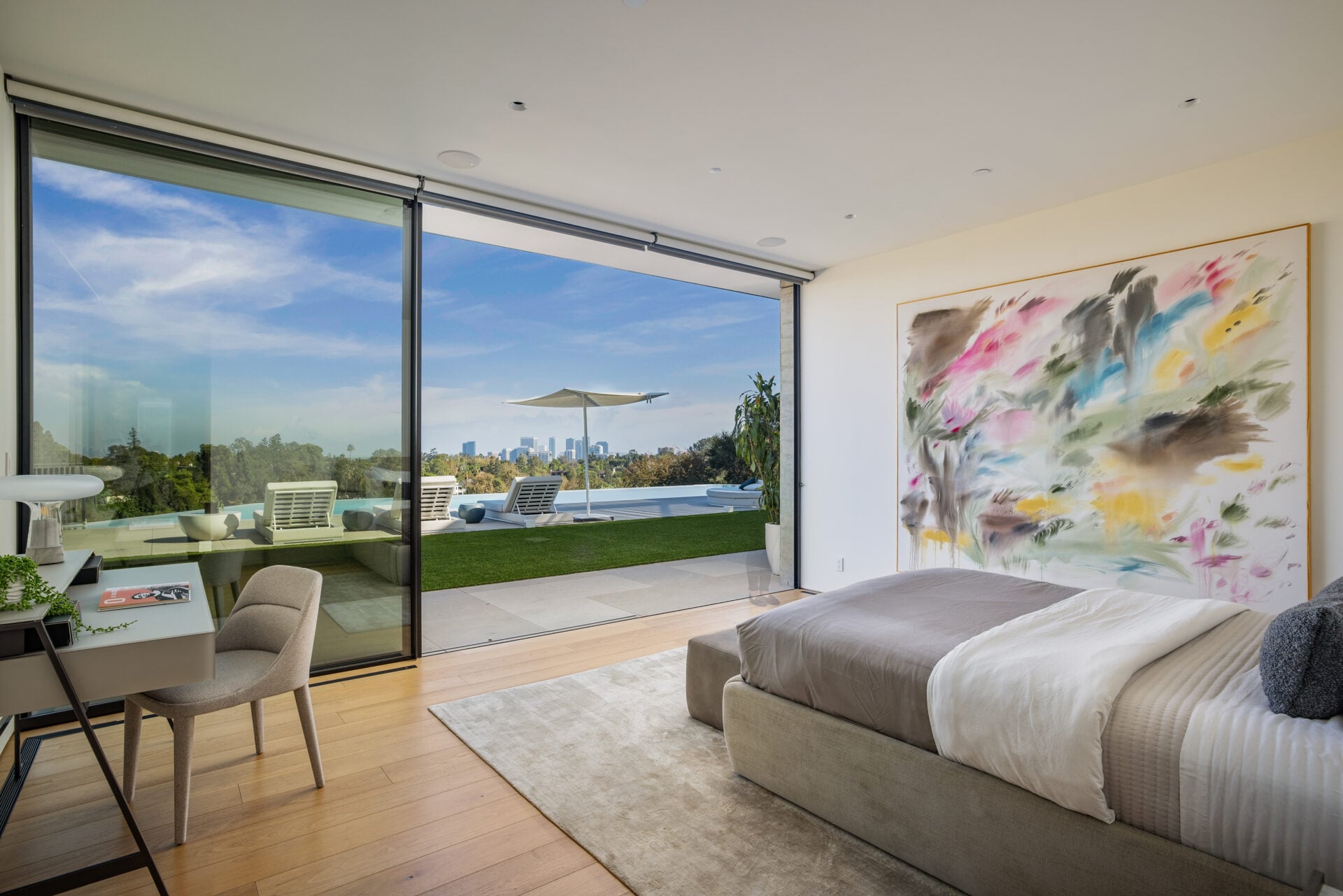 The second suite sits closer to the home’s entertainment spaces, with sliding glass opening the bedroom directly onto the pool terrace