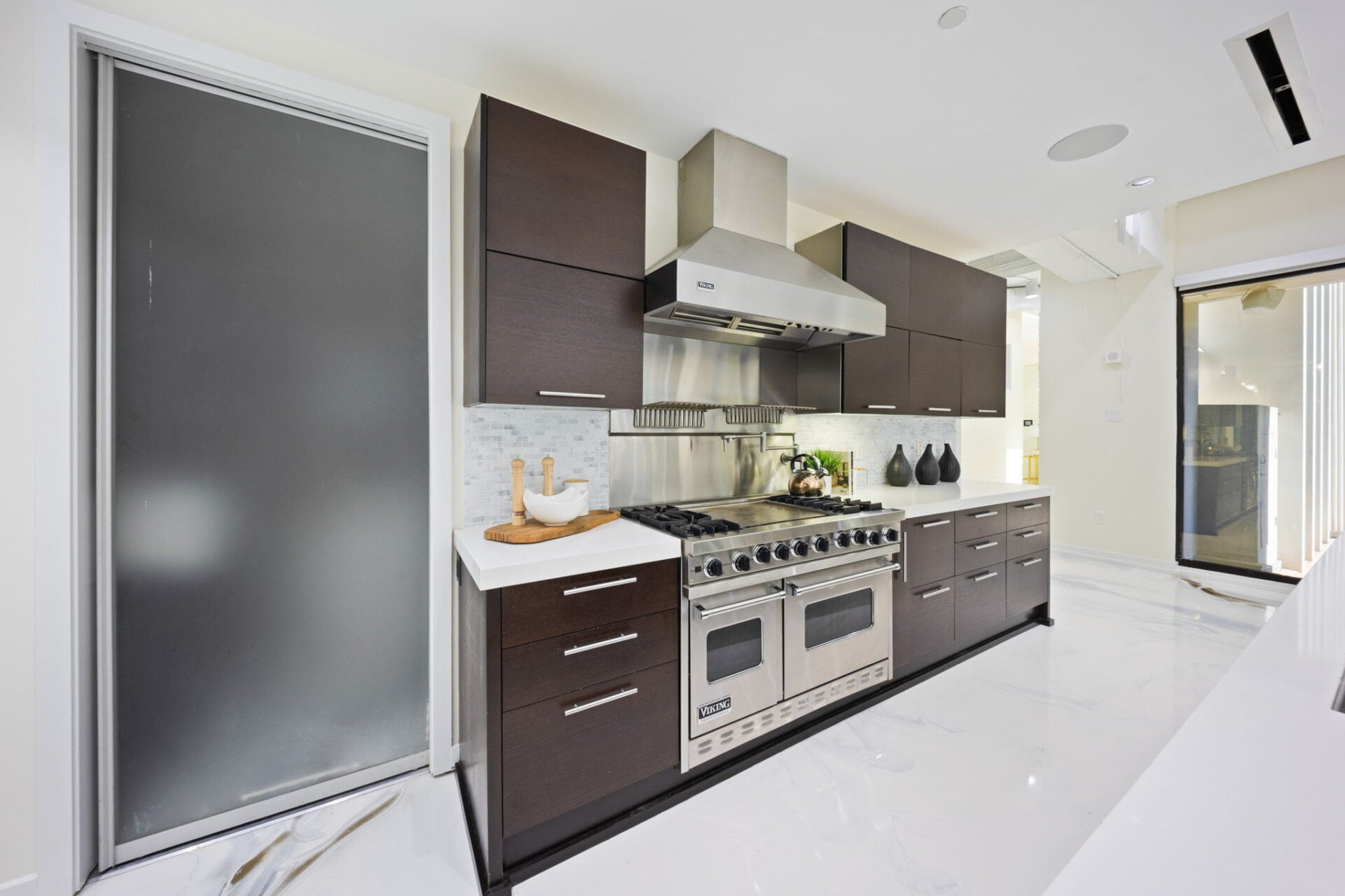 A stainless-steel Viking range sits within additional rows of cabinetry and white countertops.