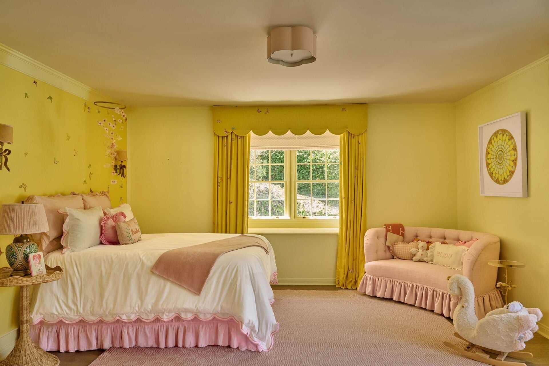 A pale pink sofa creates a small sitting area across from the bed, while floral details and white bedding offset the bright yellow walls.