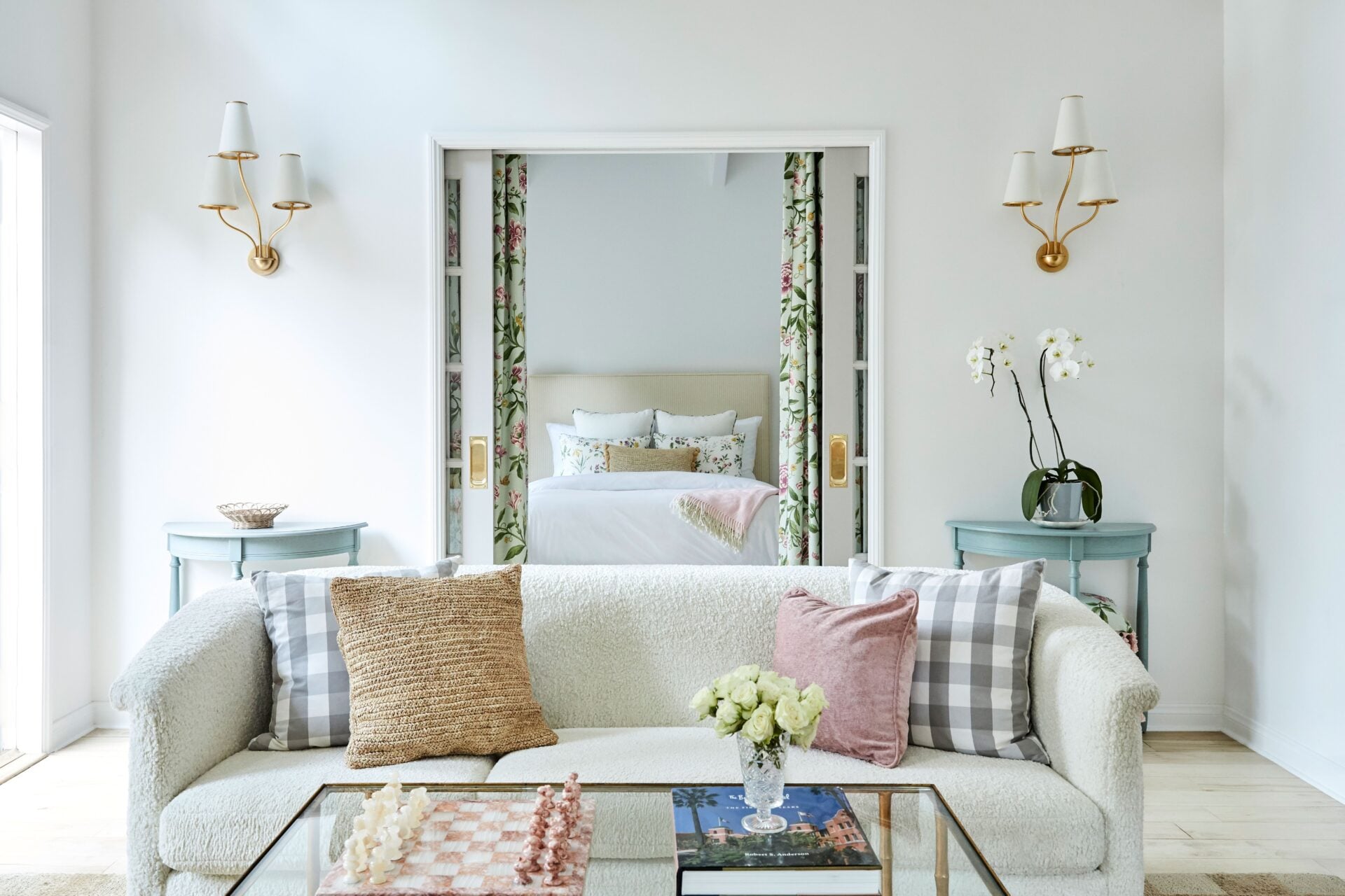 The living area opens beneath vaulted exposed-beam ceilings, with sliding doors framing the bedroom behind it.