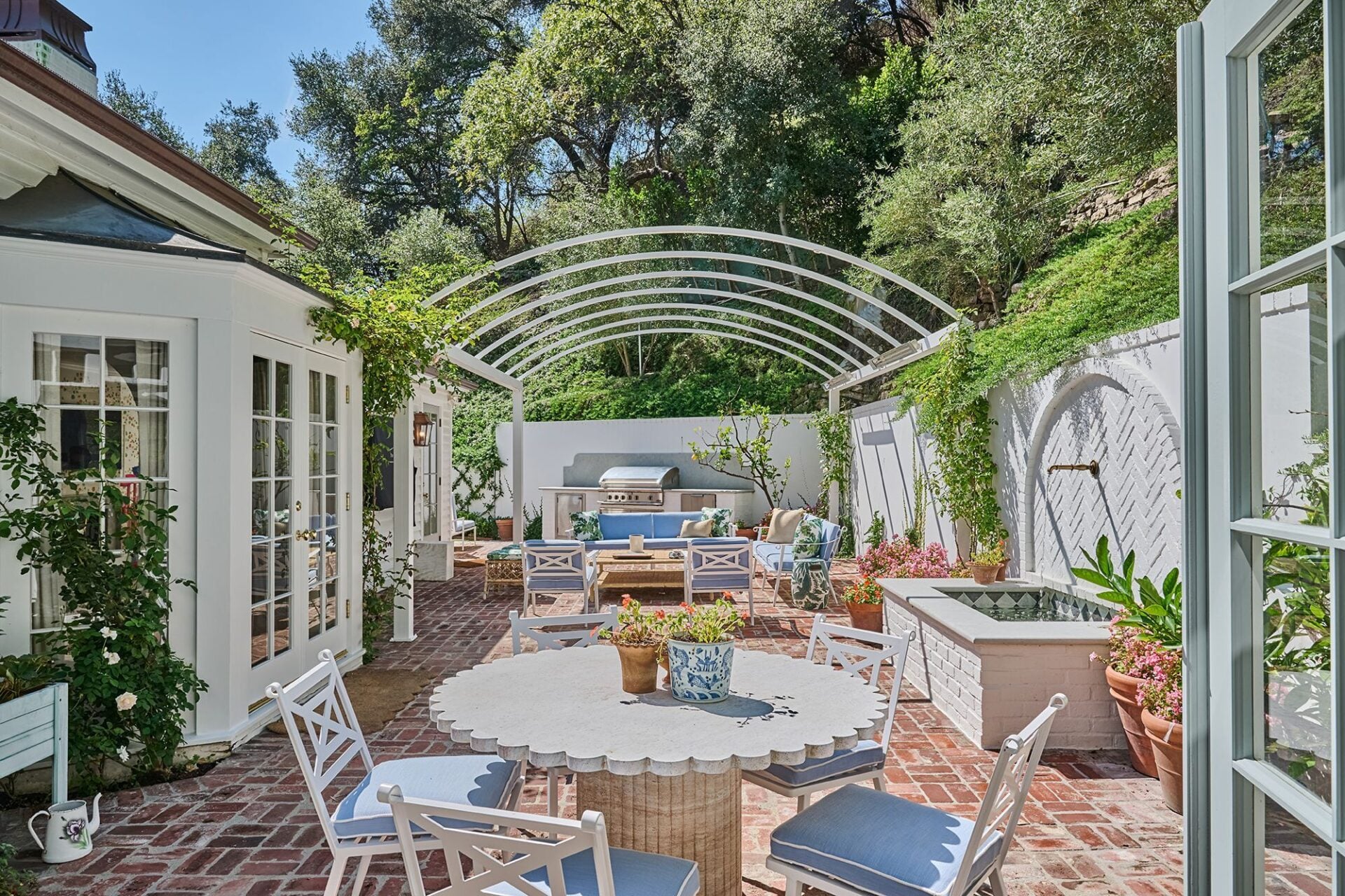 Brick patios create separate areas for dining and lounging, with fountains, fire pits, and a built-in barbecue.