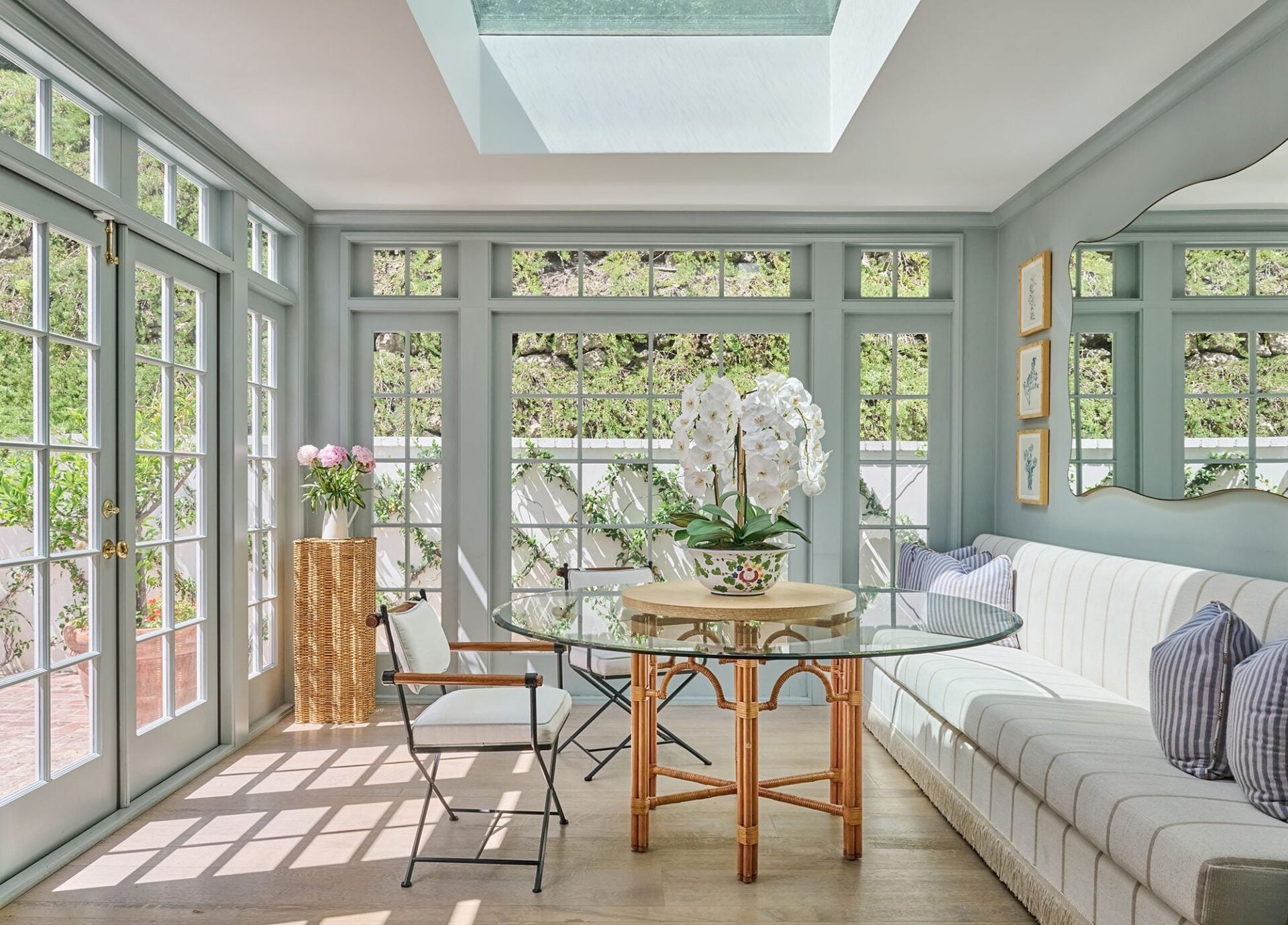 An atrium-style breakfast room is wrapped in windows and French doors, with a large skylight overhead bringing even more light into the space.