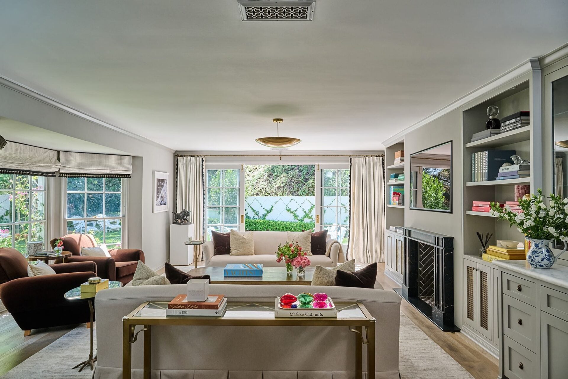 The living room opens toward the back patio through a wall of French doors, with the main seating area placed in front of a dual-sided fireplace.