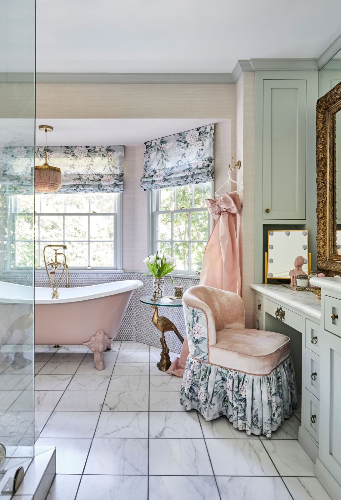 Across from the pink tub is a glass-enclosed shower and off to the side is a makeup vanity area.
