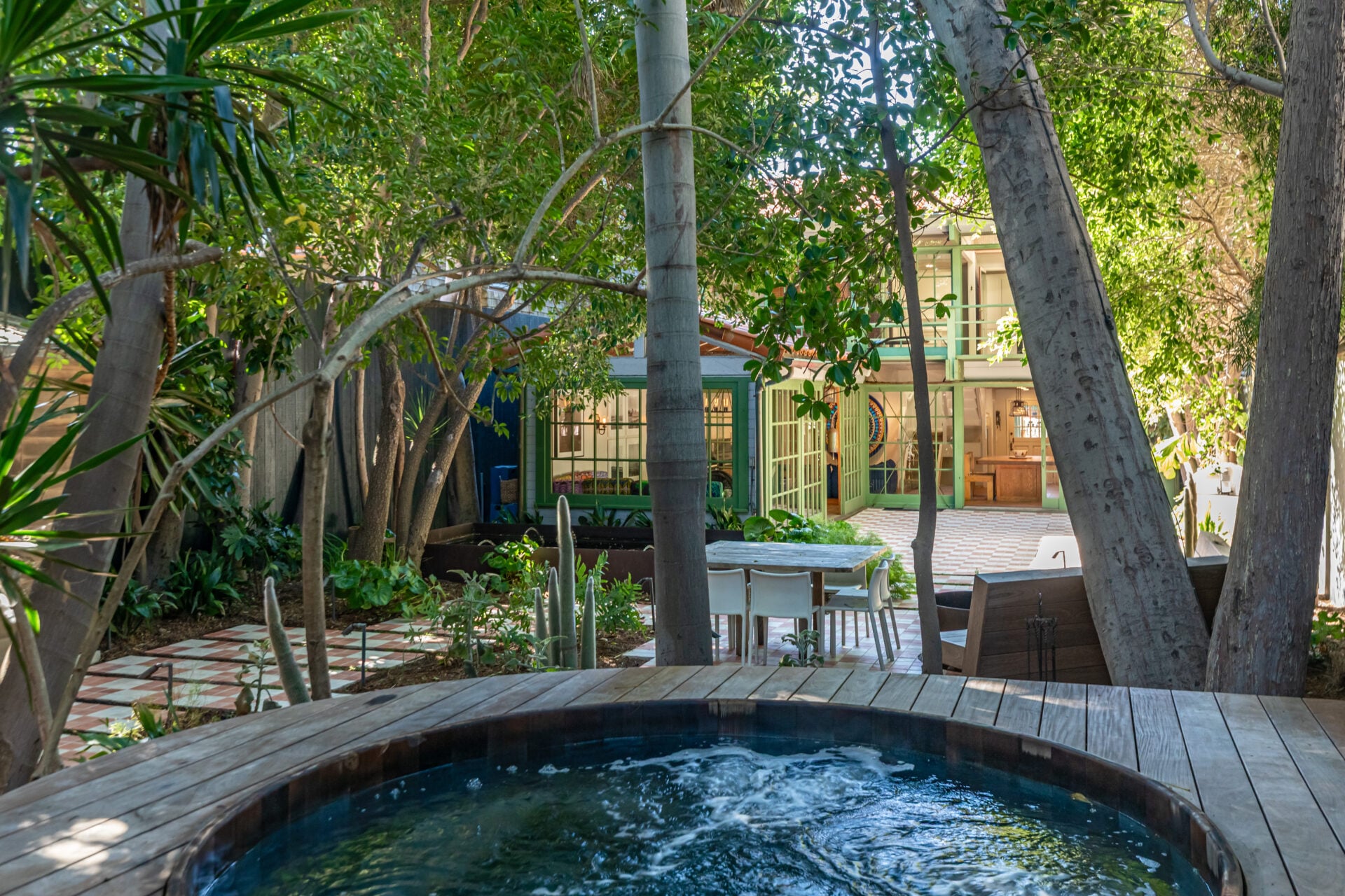 A large cedar hot tub surrounded by greenery.