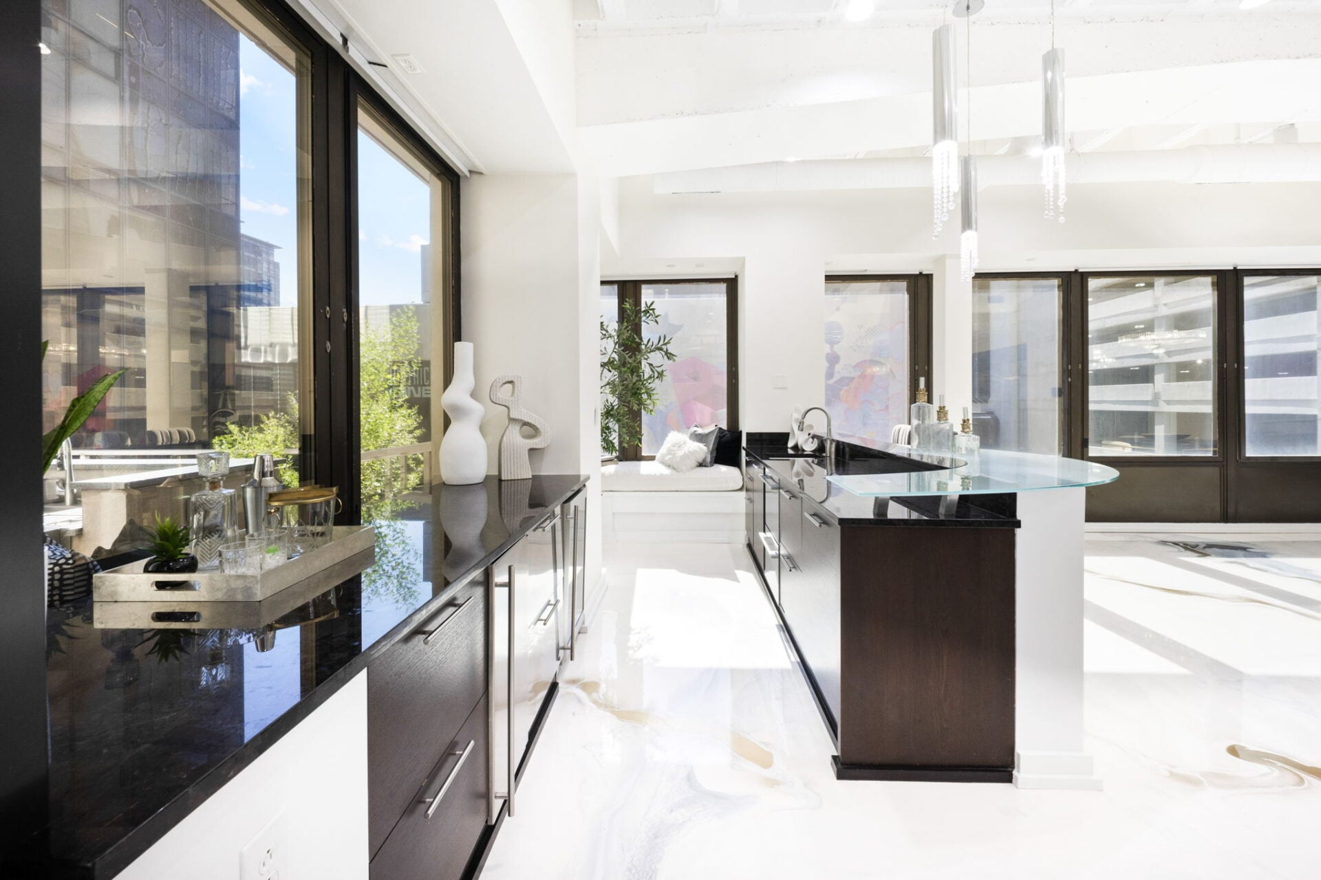 A custom bar is placed in the corner beside the terrace doors, with a long black stone counter running beneath the windows.