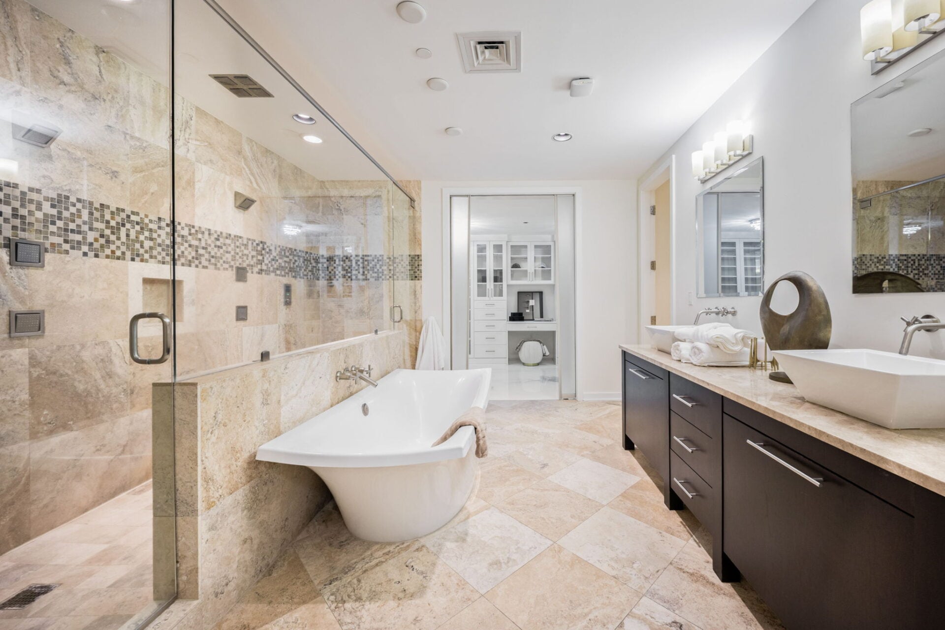 A freestanding tub placed between the glass-enclosed shower and a long double vanity.