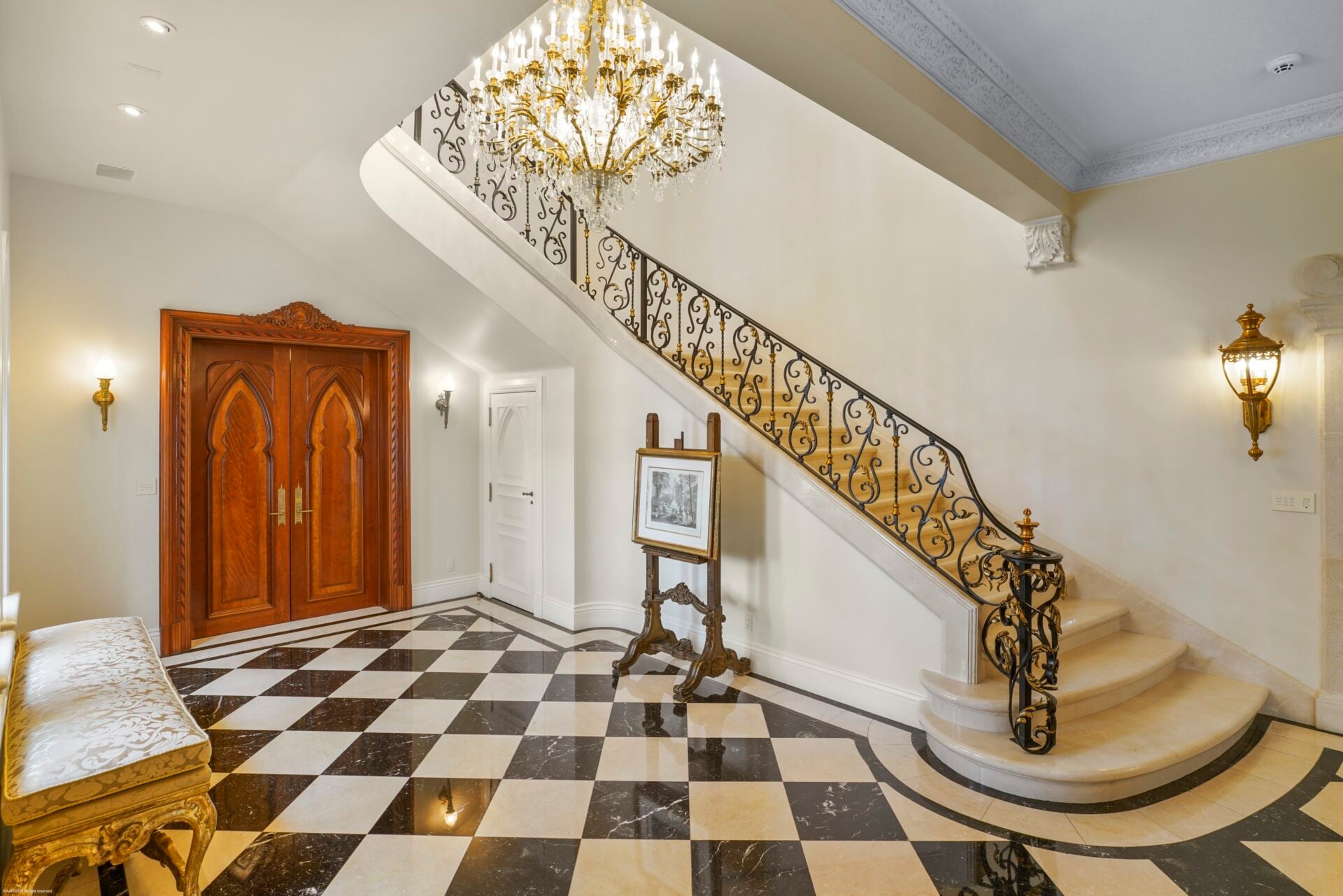 A curved staircase rises along one side with decorative ironwork and gold accents carrying the formal design upward.