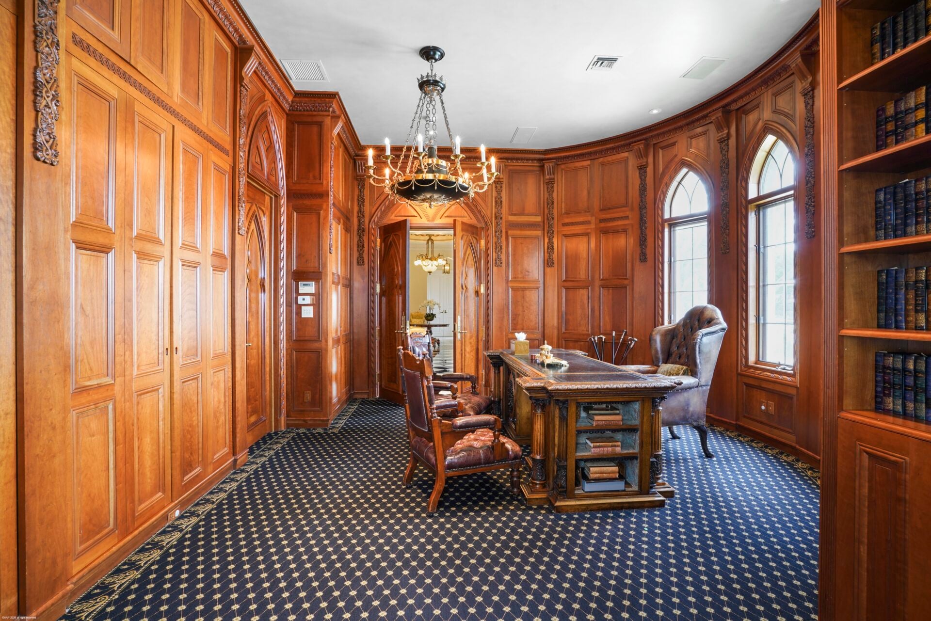 Right off the foyer, the home office is wrapped in carved wood paneling across the walls and built-in bookcases. 