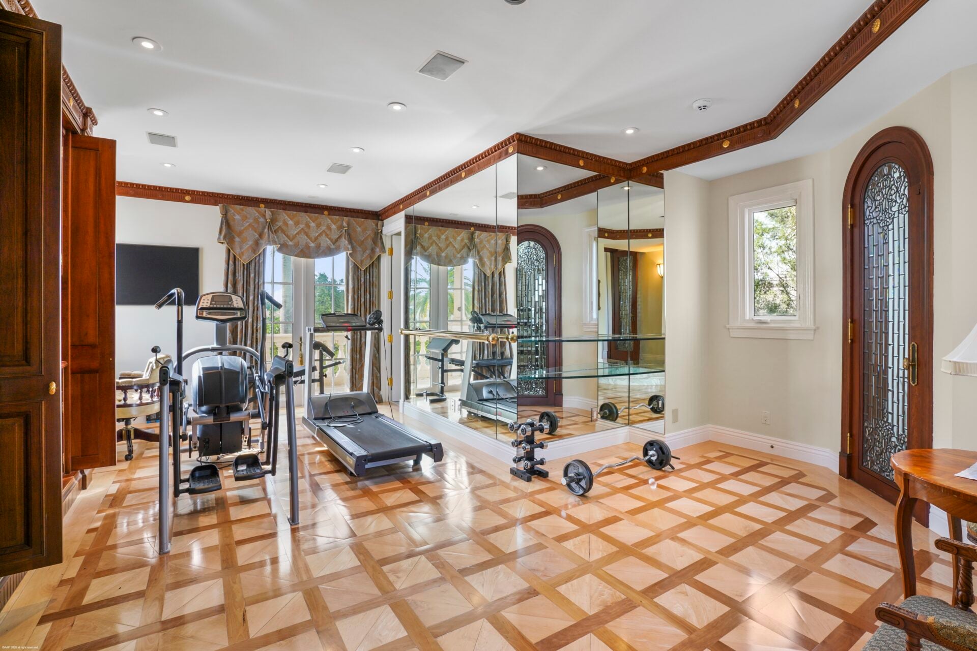 The fitness center is a bright, open room with patterned wood flooring and a mirrored corner wall.