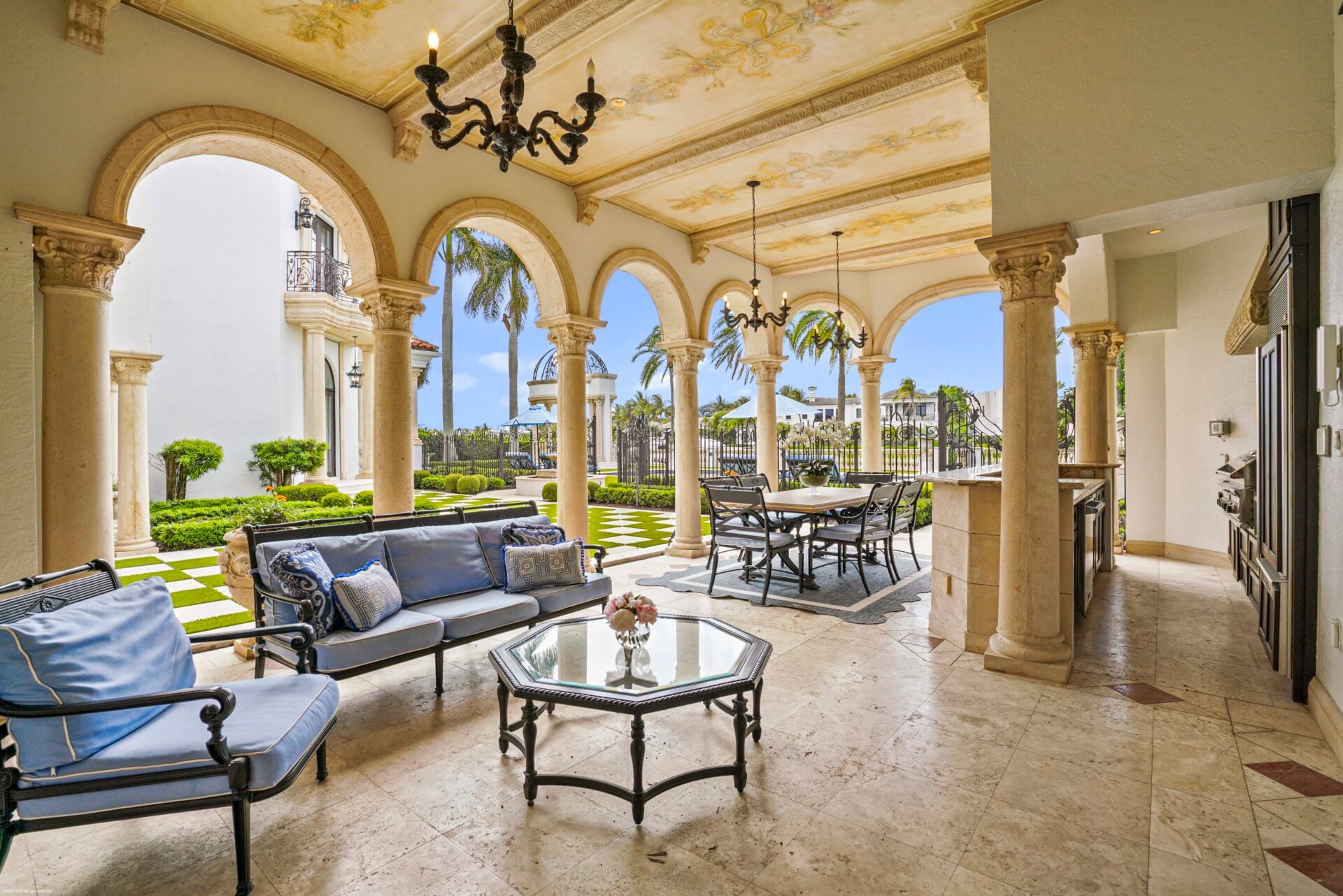 One side of the covered terrace is set up as a lounge with light blue cushioned seating around a glass coffee table.