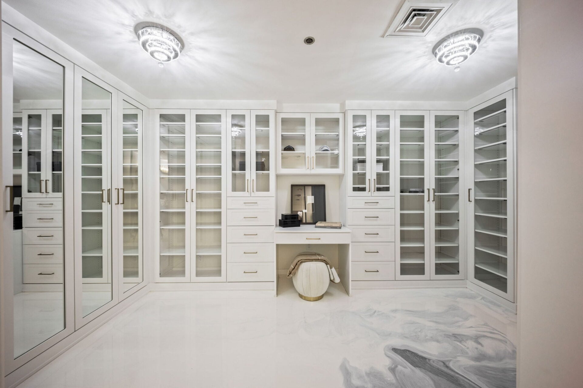 A dressing room wrapped in floor-to-ceiling glass-front cabinetry.