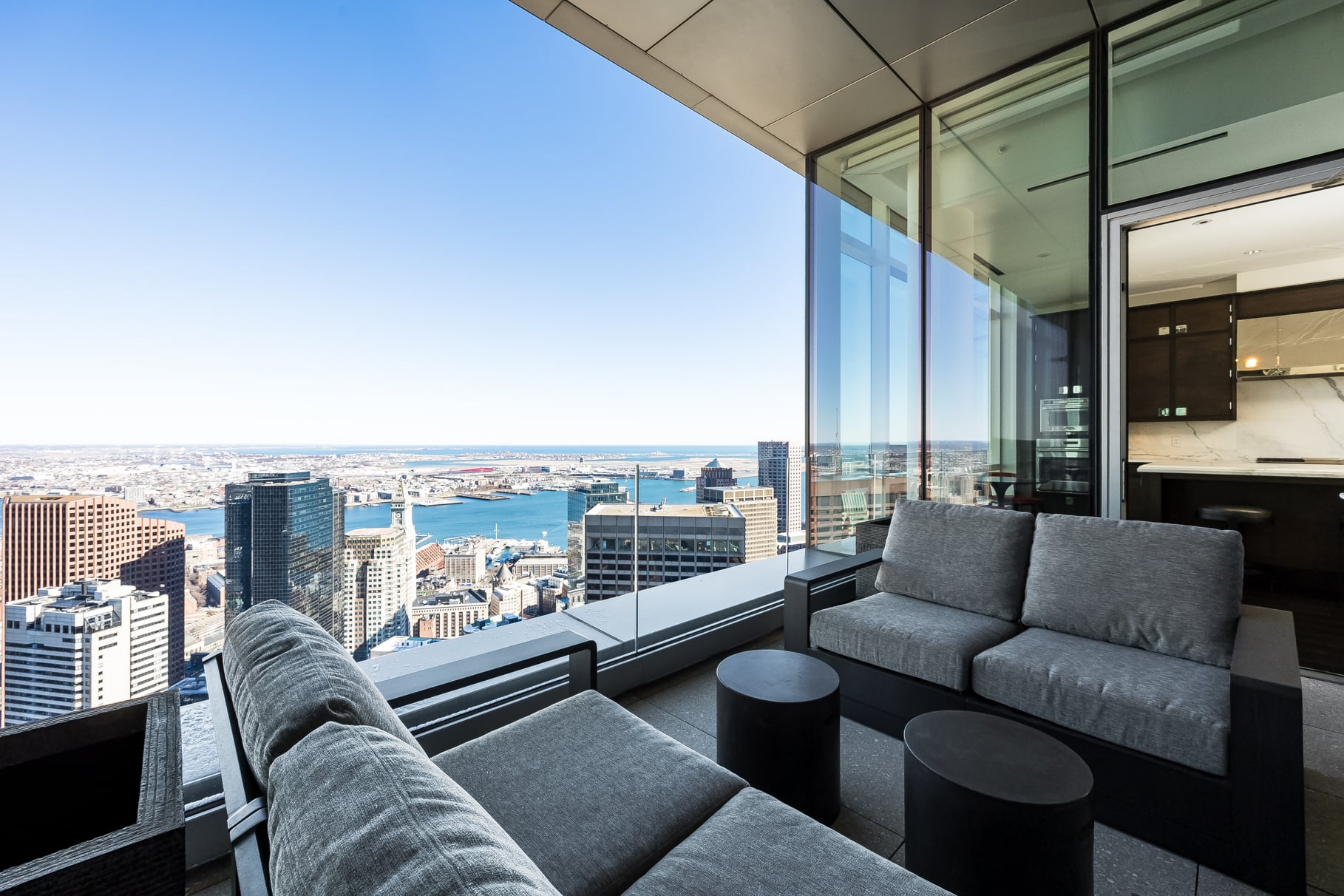 The private terrace extends the main living spaces outside with a covered seating area set behind a clear glass railing.