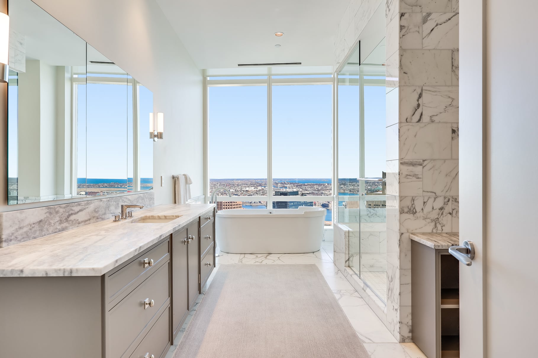 A long vanity running along one side and a freestanding soaking tub placed at the back of the room in front of the windows.