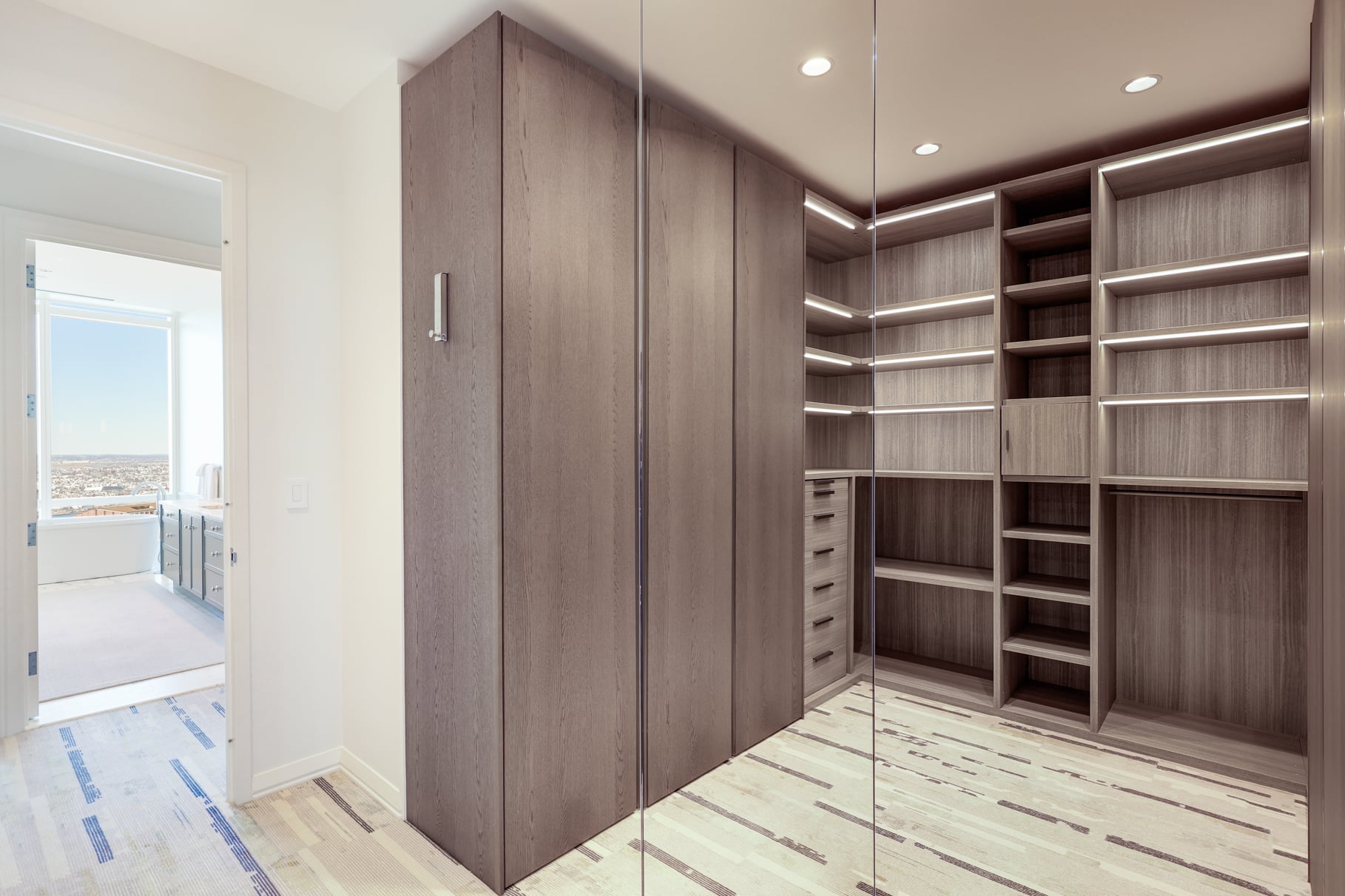 Right outside the bathroom, the suite continues into a walk-in closet finished with dark wood cabinetry.