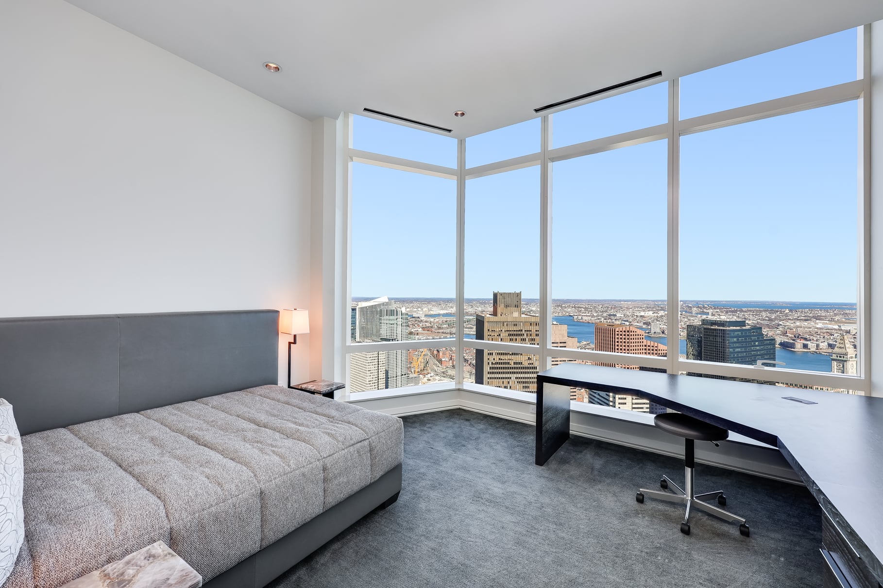 A second bedroom is currently set up as a home office, with an L-shaped desk placed against the window and a daybed behind it.