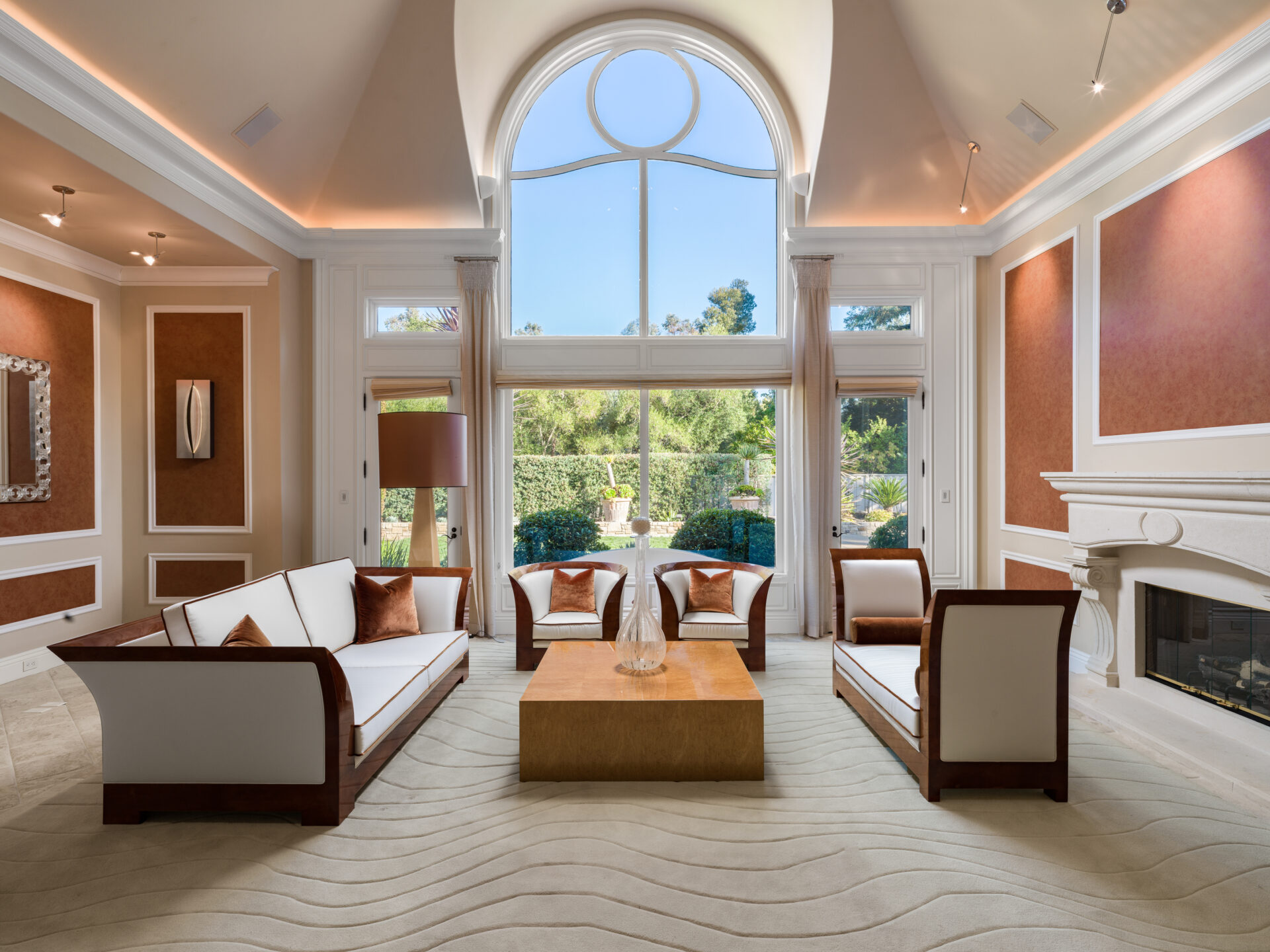 French doors and additional panes of glass extend across the back wall, while a carved fireplace runs along the right side.