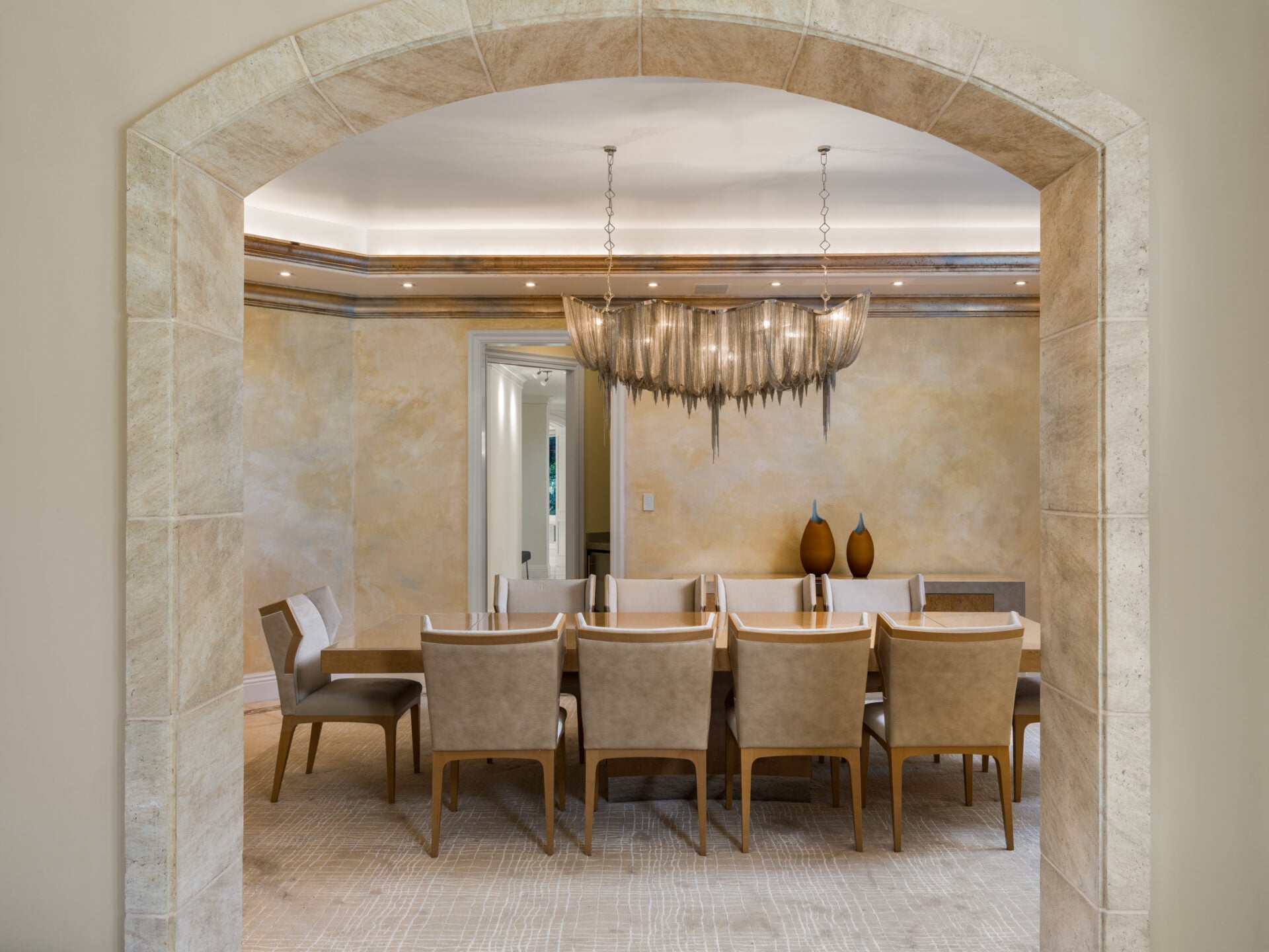 The formal dining room opens past a stone archway.