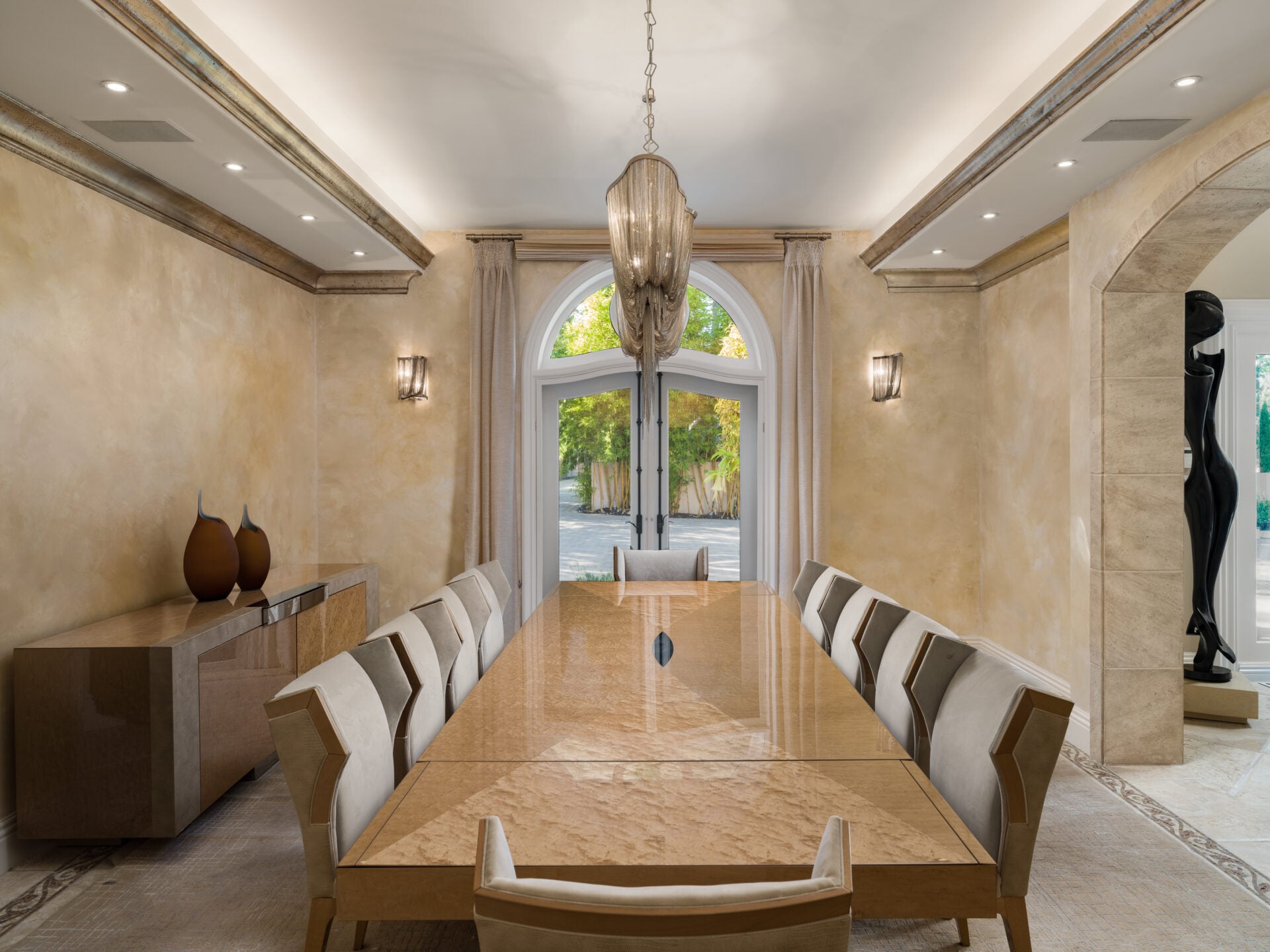 A long dining table runs through the center beneath a suspended chandelier.