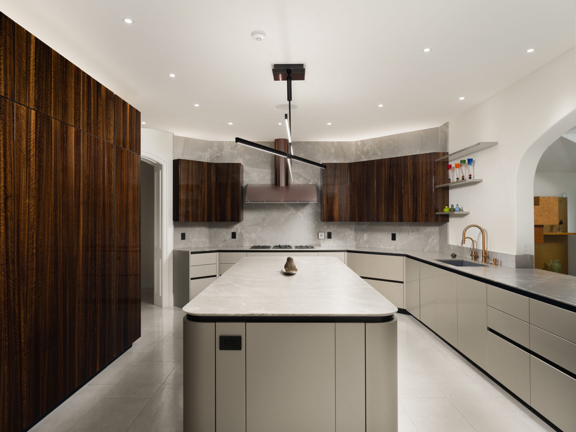 The kitchen has a more contemporary design with rare eucalyptus cabinetry rising along one wall and lighter lower cabinets wrapping around a curved center island.