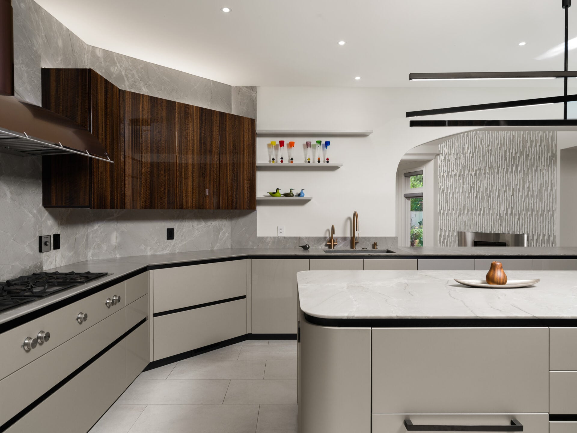 Stone surfaces continue across the counters and backsplash with integrated designer appliances.