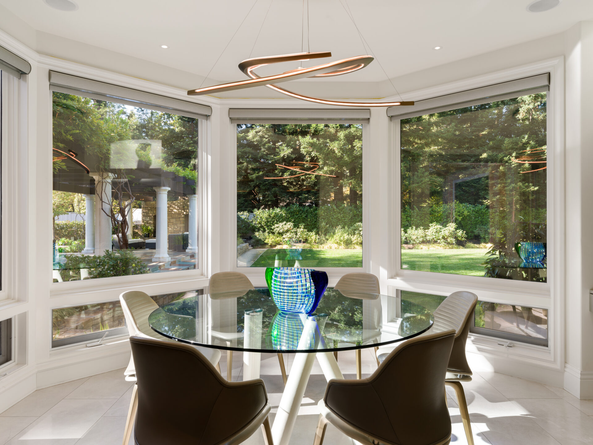 At the far end, the kitchen opens into a rounded breakfast nook enclosed by oversized windows.