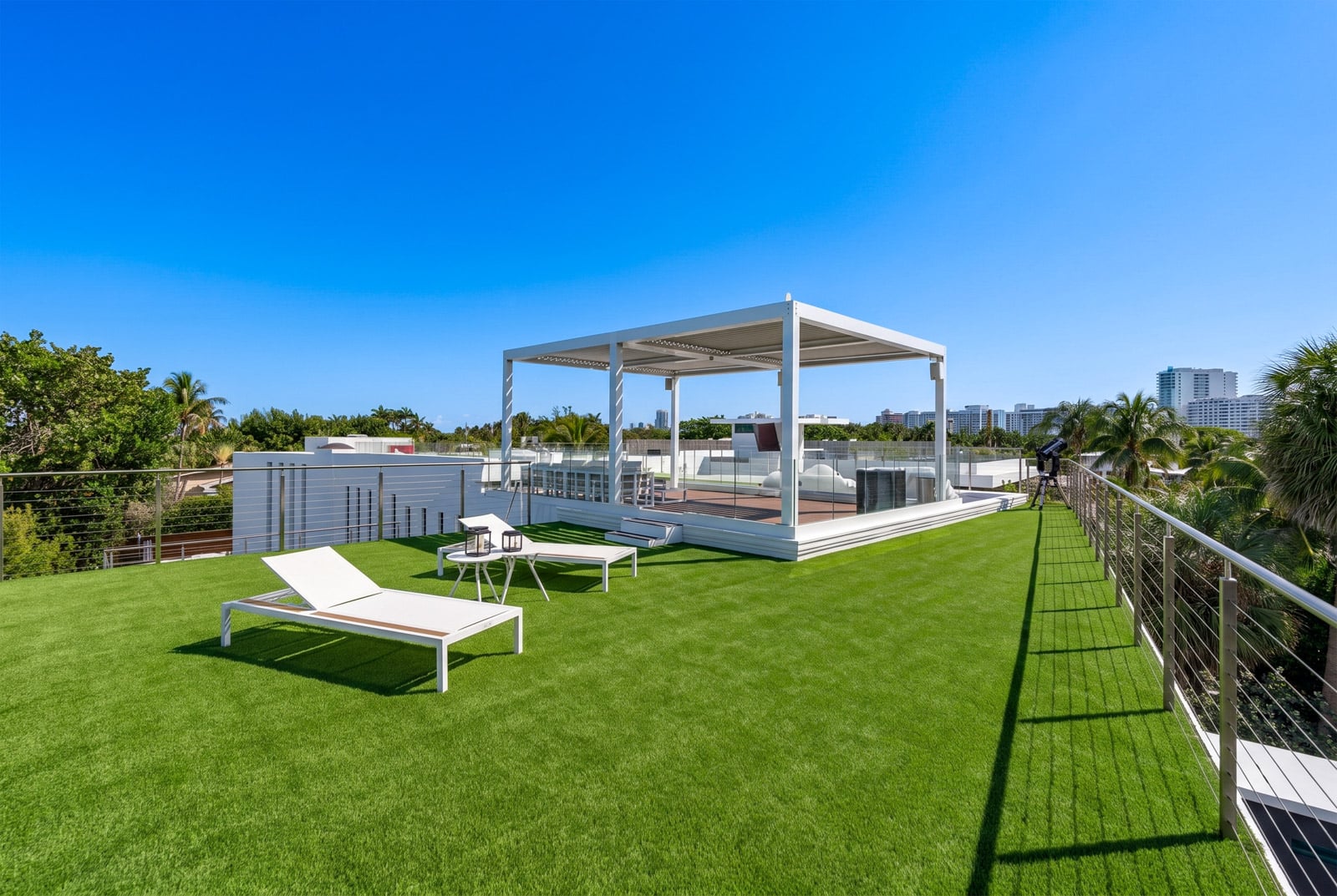 At the top, the roof expands into an open-air lounge with additional seating and sunbathing space spread across the artificial lawn. 
