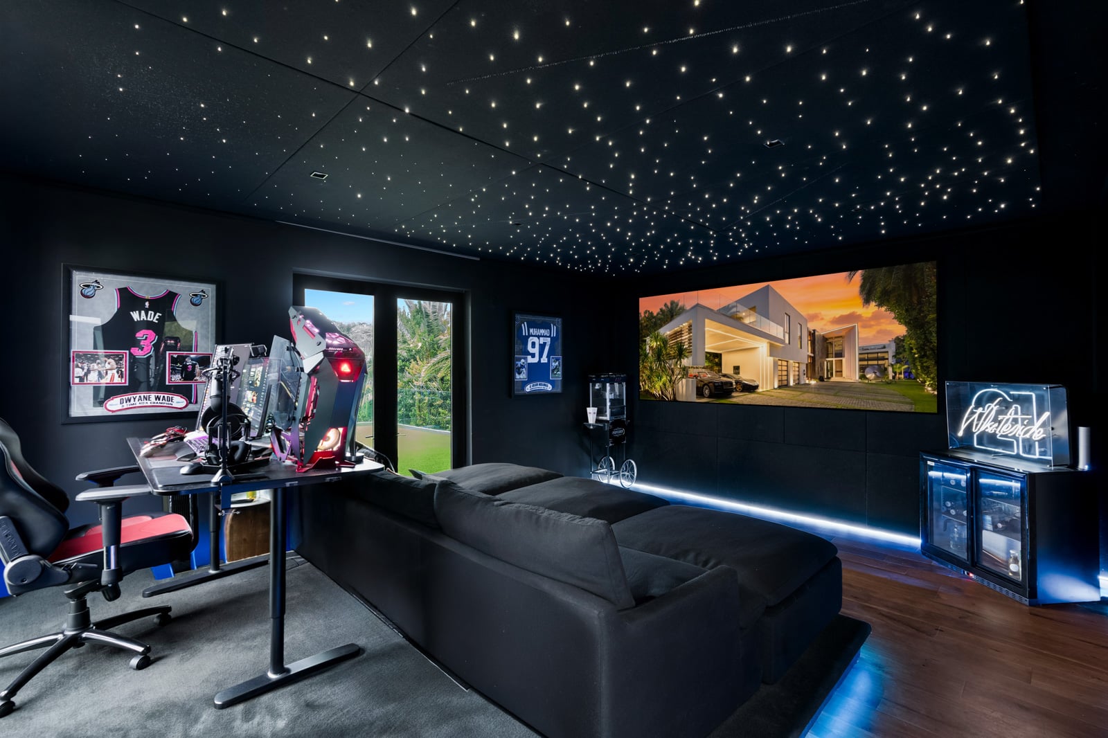 The theater is wrapped in dark walls with a star-like ceiling of tiny lights stretching over a large screen and a deep sectional.