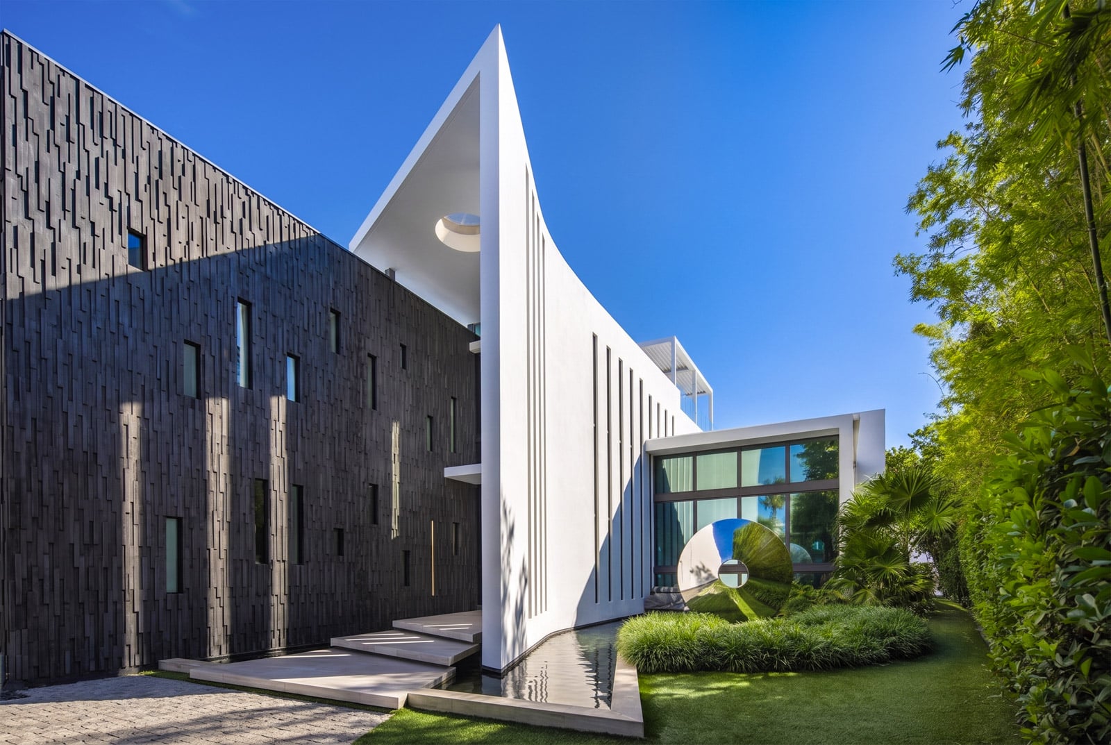 A shallow reflecting pool runs alongside the steps, passing by landscaped greenery and a reflective sculpture.
