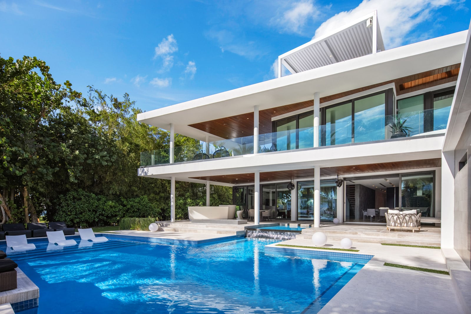 A pool and raised spa sit directly off the covered entertaining areas beneath the house’s deep overhangs.