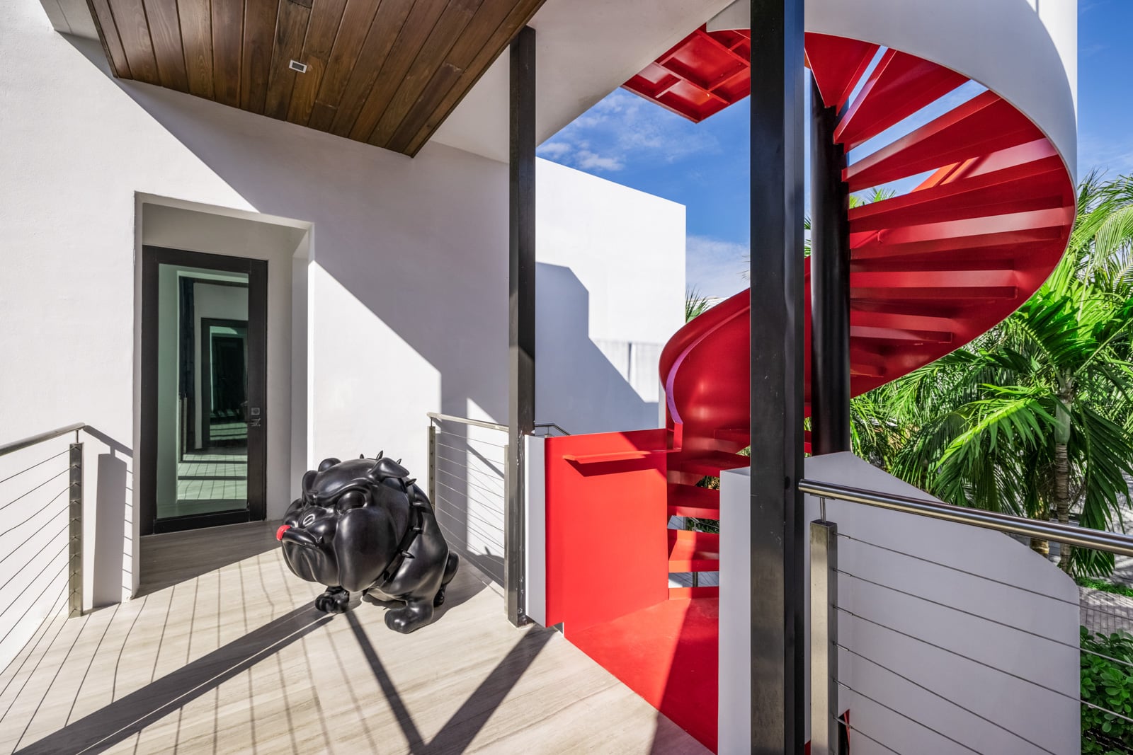 A bright red spiral staircase links the mansion’s lower levels before continuing to the rooftop terrace. 