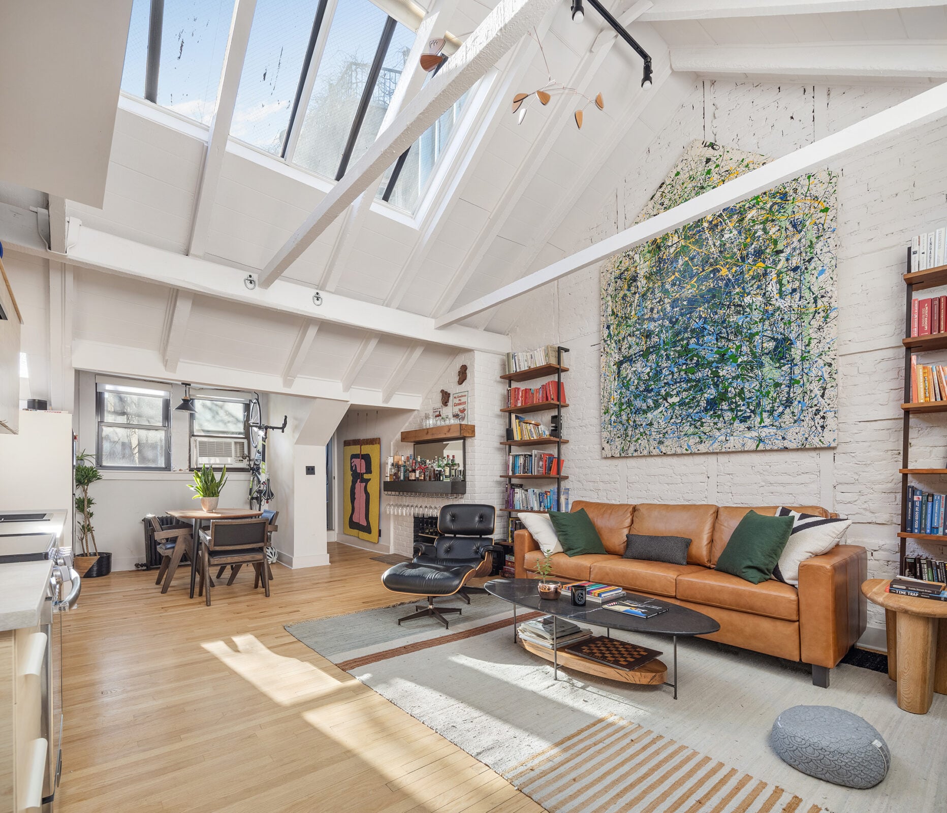 A large skylight runs along one side of the roofline, pulling daylight across the open living room and down toward the dining area at the far end.