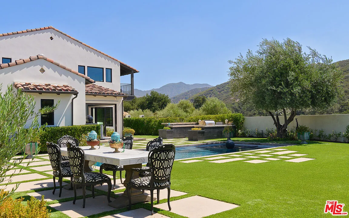 An outdoor dining area is placed on the other side of the pool terrace.