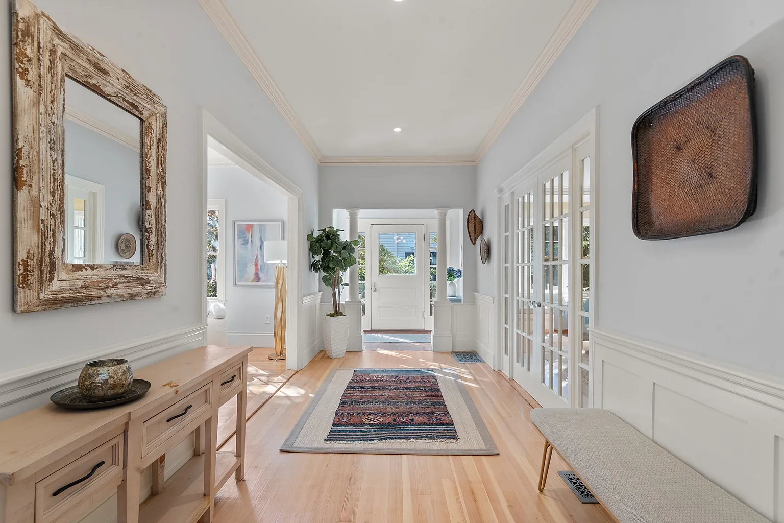 The entry opens into a long central hall with pale blue walls painted above white paneled wainscoting.